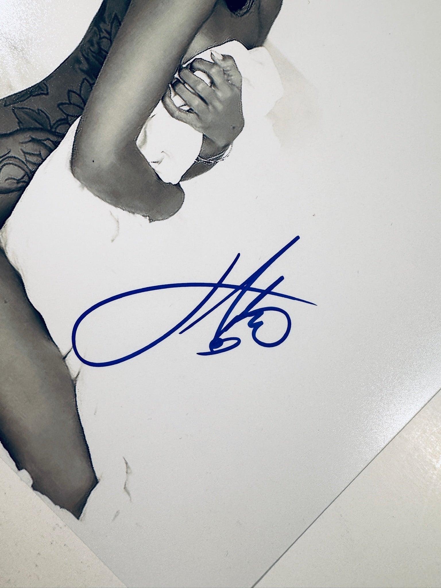Close-up view of Jhene Aiko's blue signature across the white sheet and bed on the promotional photograph.