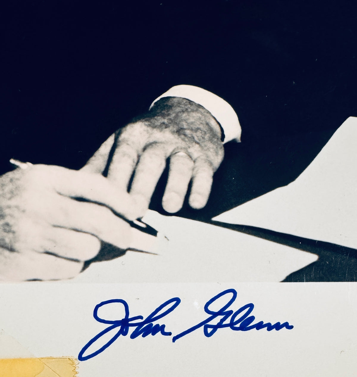 Close-up view of John Glenn autograph signature in blue pen on the bottom border of the photo.
