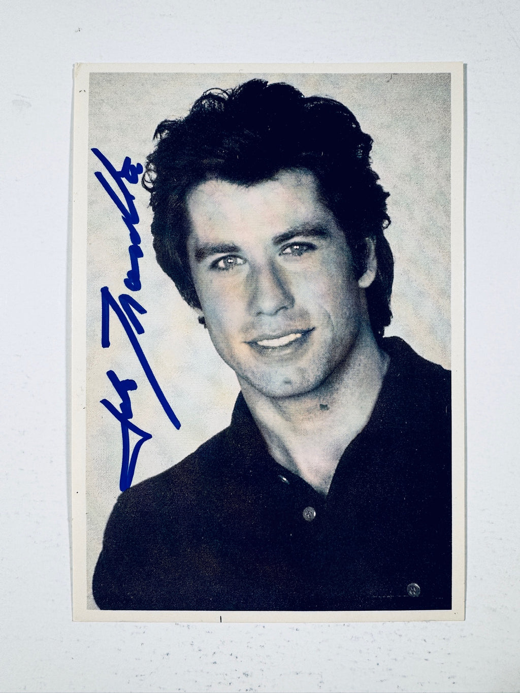 Full view black and white headshot photograph of actor John Travolta hand-signed in blue ink.