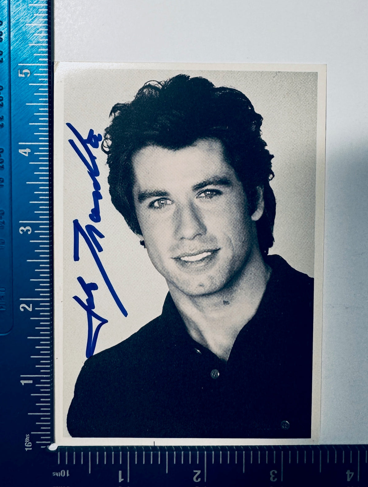 Autographed John Travolta promotional photo displayed alongside a measuring ruler for exact dimensions.