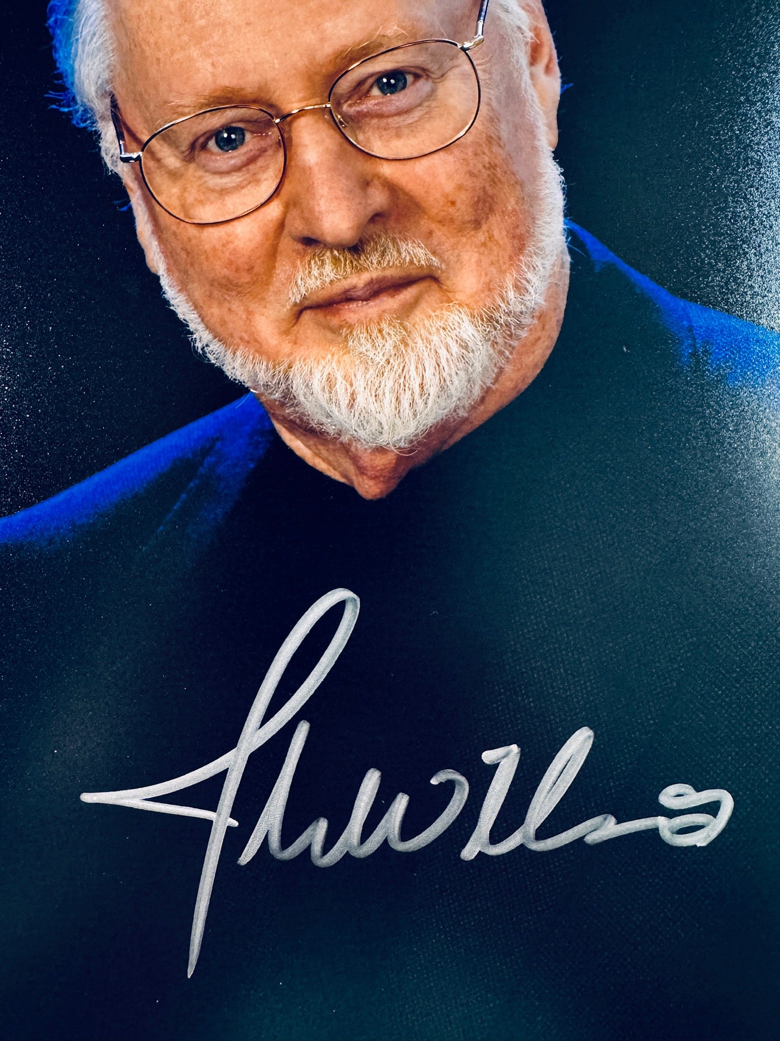 Close-up view of John Williams's signature in silver marker across the composer promotional matte photo.