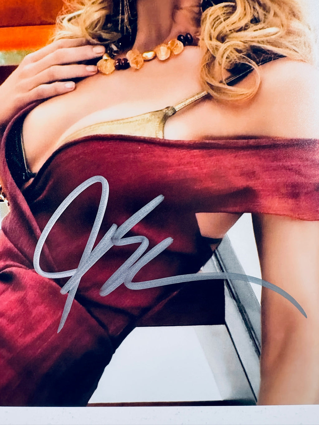 Close-up view of Joy Bryant's silver signature across her red dress on the promotional photograph.