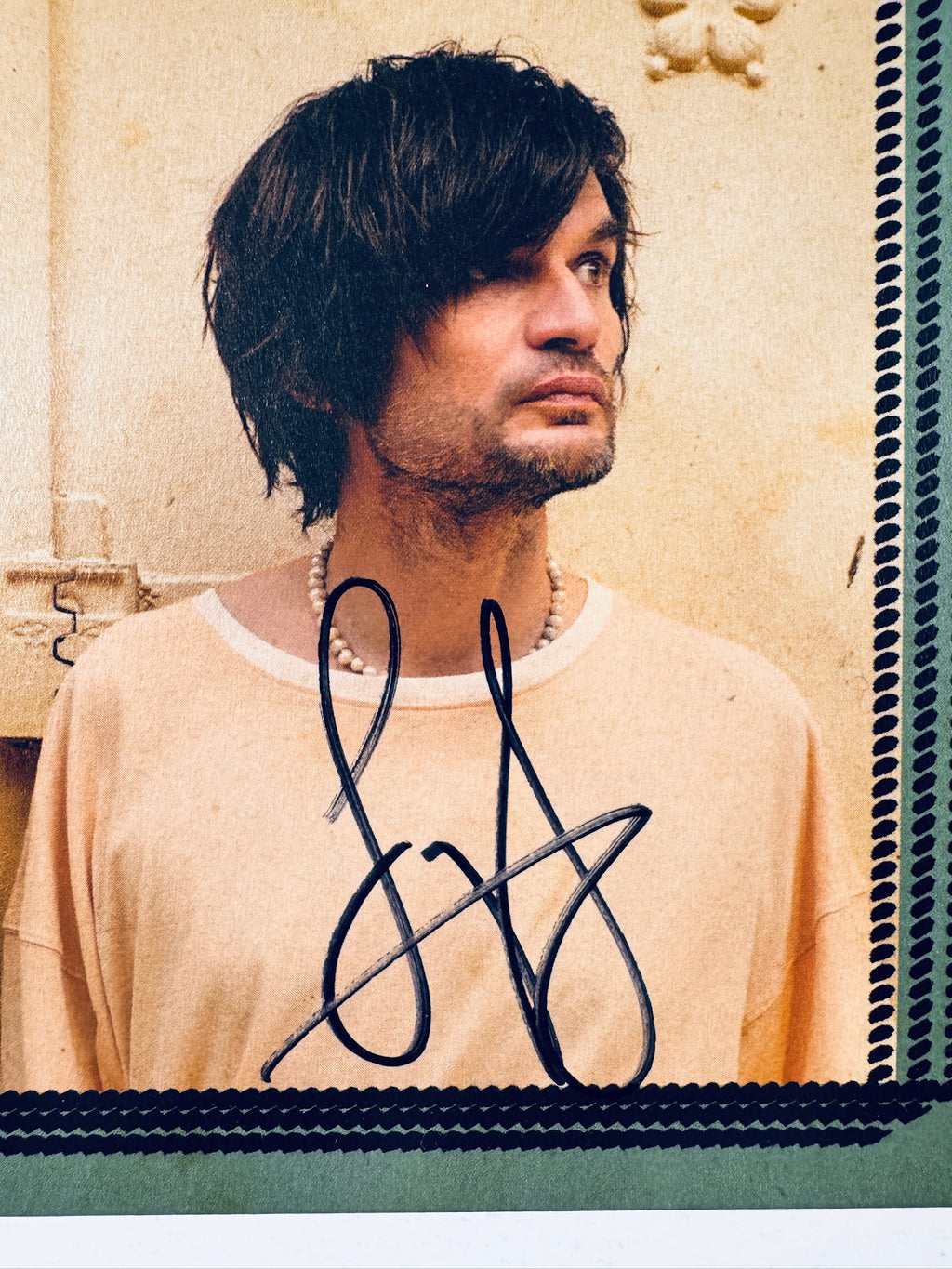 Close-up view of the handwritten autograph signatures by Jonny Greenwood and Dudu Tassa on the front cover of the Jarak Qaribak vinyl record.