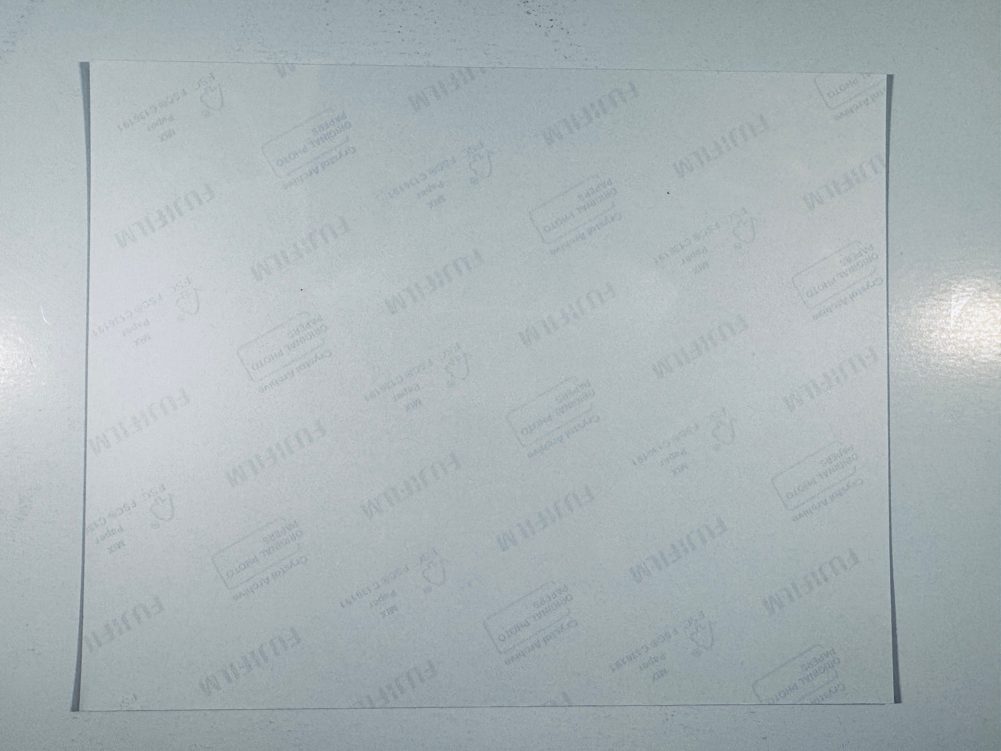 The plain white reverse side of a photographic print showing translucent Fujifilm crystal archive paper watermarks and logos.
