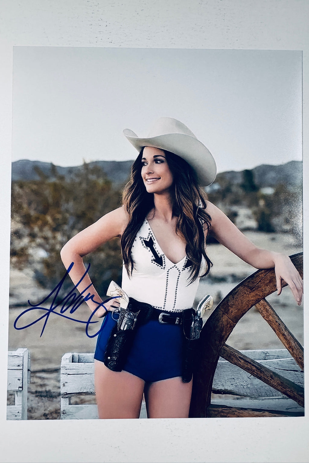 Kacey Musgraves hand-signed 8x10 matte photo wearing a cowboy hat and cowgirl outfit with holsters outdoors.