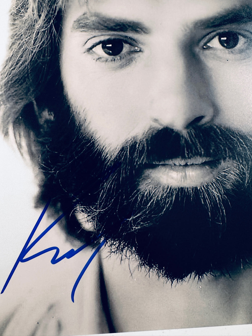 Close-up view of Kenny Loggins's signature in blue marker across the vintage black and white matte photo.