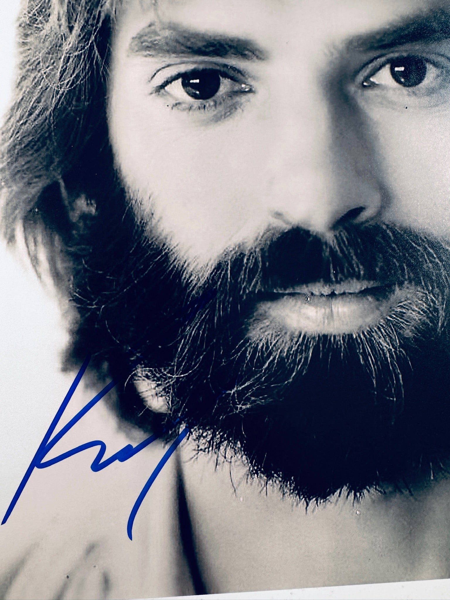 Close-up view of Kenny Loggins's signature in blue marker across the vintage black and white matte photo.