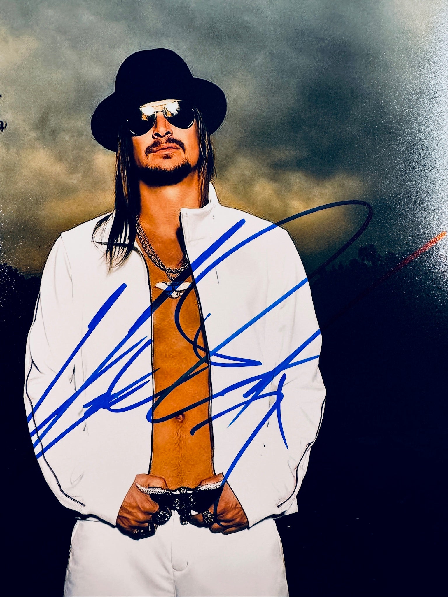 Close-up view of Kid Rock's signature in blue marker on his promotional matte photo.