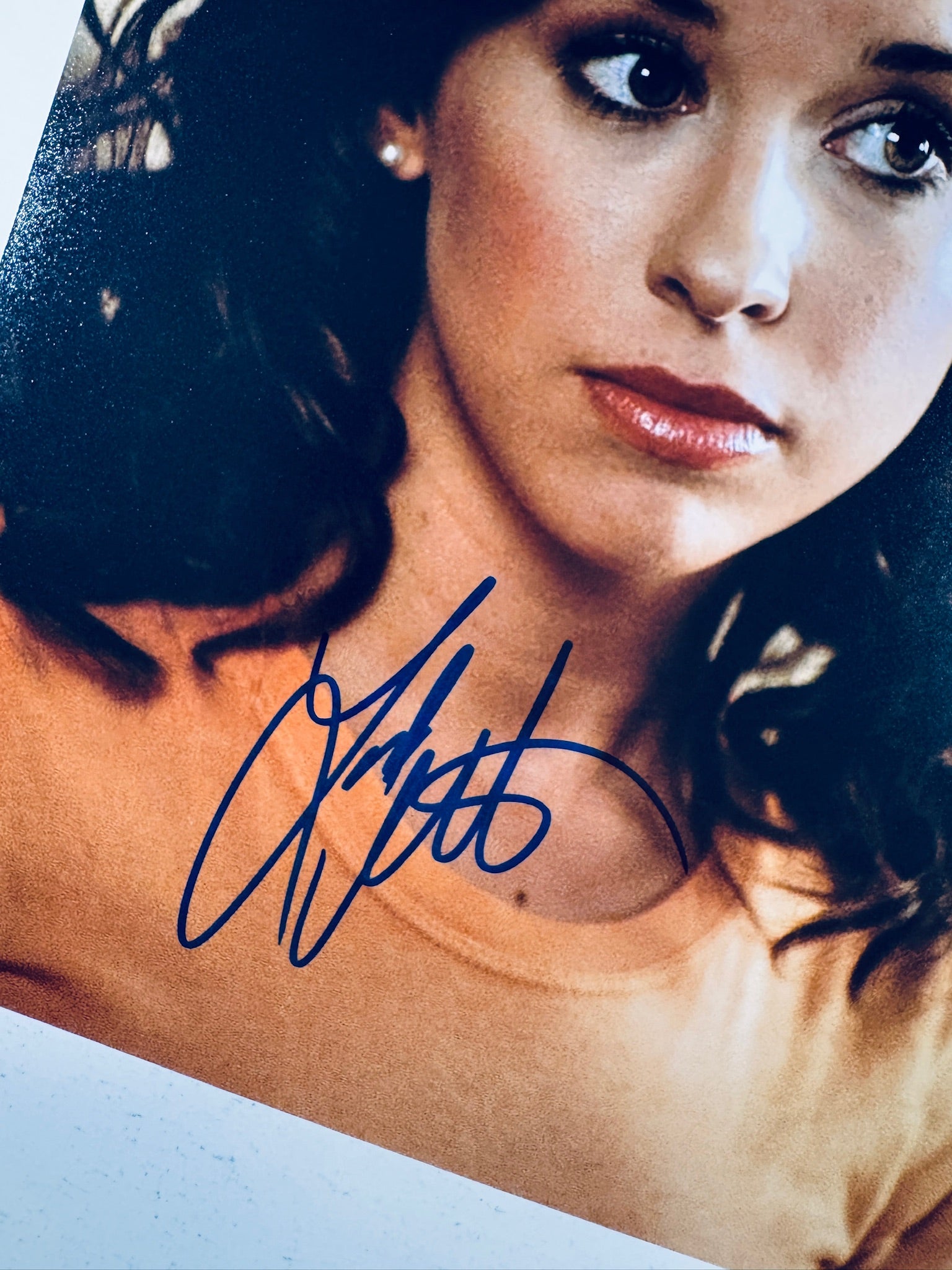 Close-up view of Lacey Chabert's blue autograph across her lower neckline on the promotional photograph.