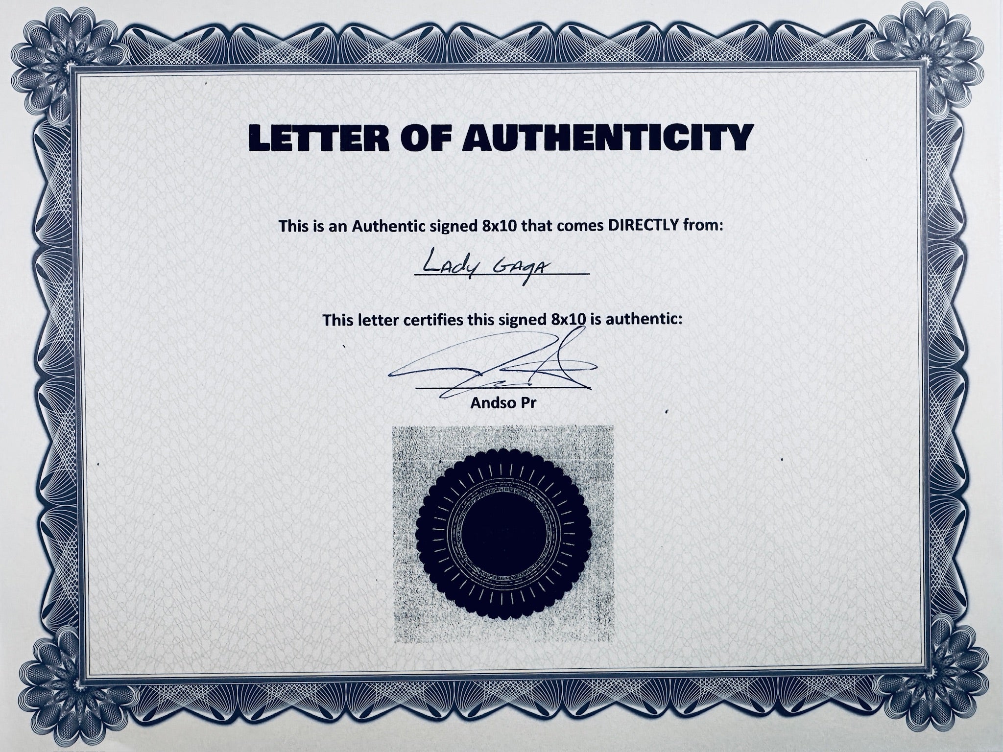 A Letter of Authenticity with a decorative blue-patterned border, certifying an authentic signed 8x10 coming directly from Lady Gaga, featuring a dark circular seal graphic at the bottom.