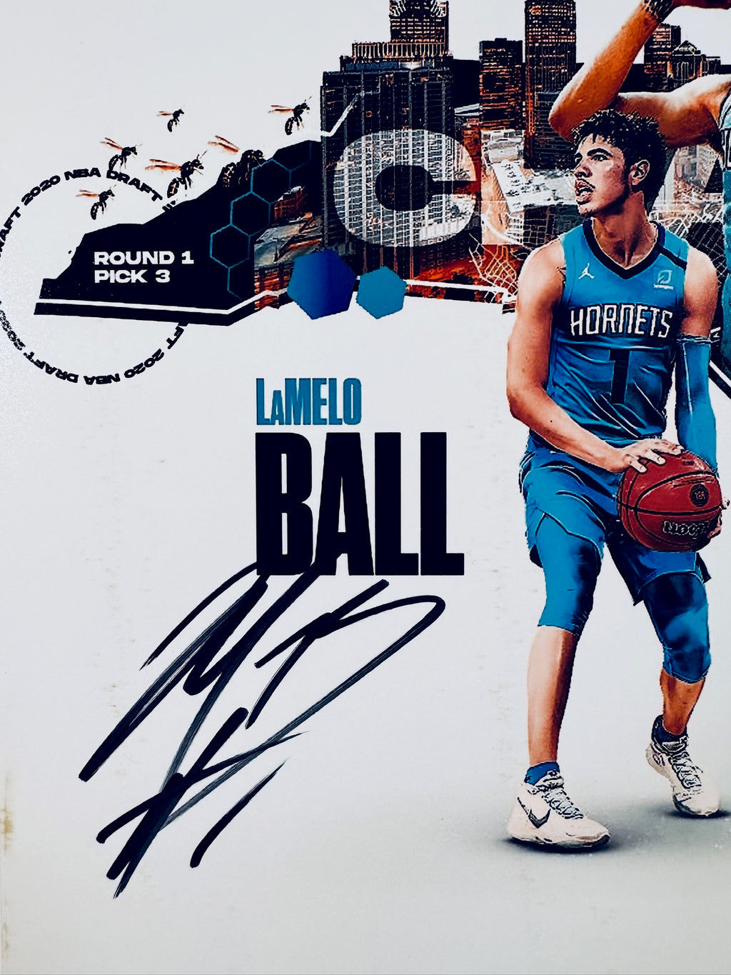 Close-up view of LaMelo Ball's signature in black marker across the light background of the Charlotte Hornets commemorative basketball photo.