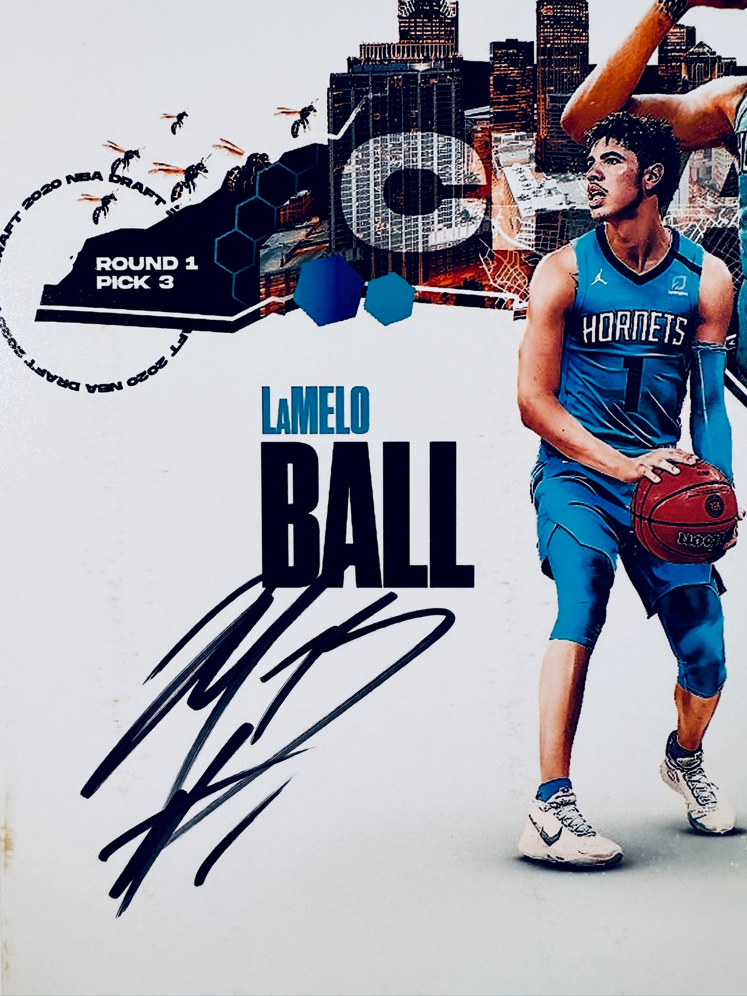 Close-up view of LaMelo Ball's signature in black marker across the light background of the Charlotte Hornets commemorative basketball photo.
