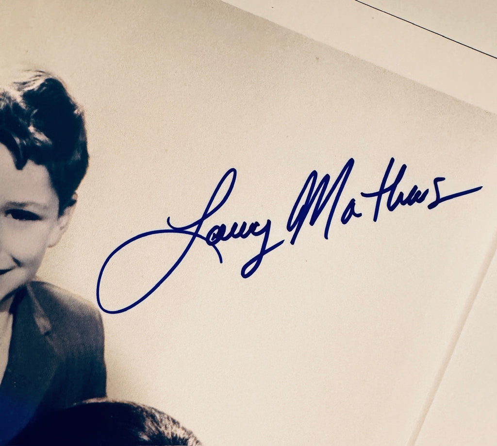 Close-up view of Larry Mathews signature in blue pen near the top right corner.