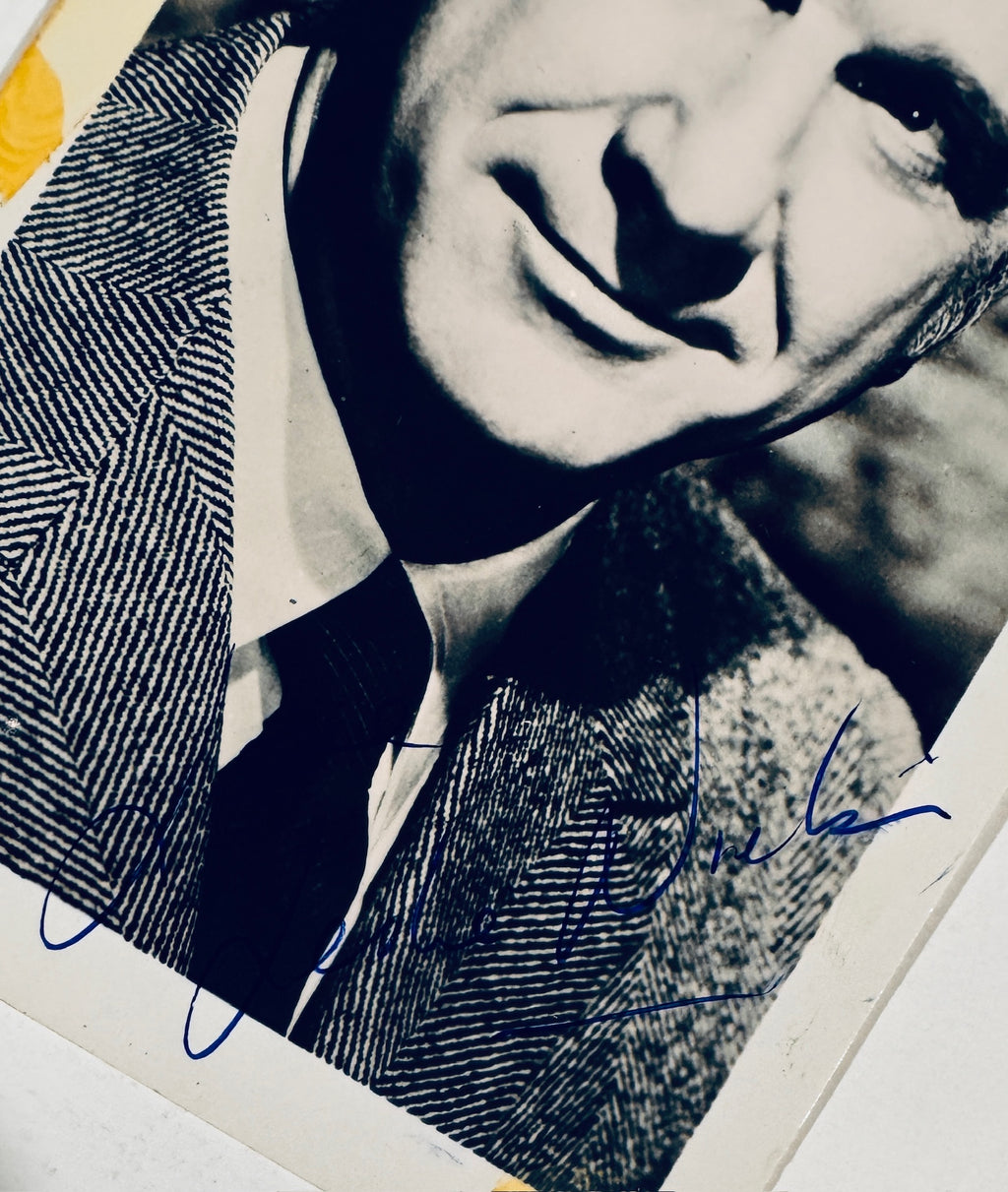 Close up detail of authentic Leslie Nielsen signature in blue ink on vintage photograph.