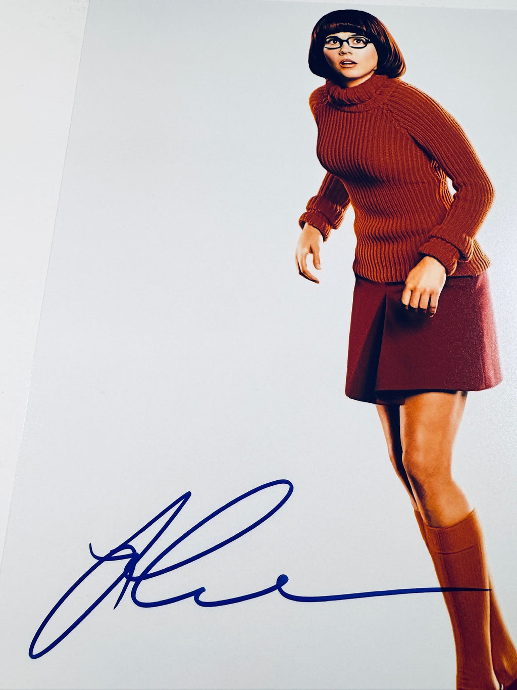 Close-up view of Linda Cardellini's signature in blue marker across the white background of the promotional Scooby-Doo photo.