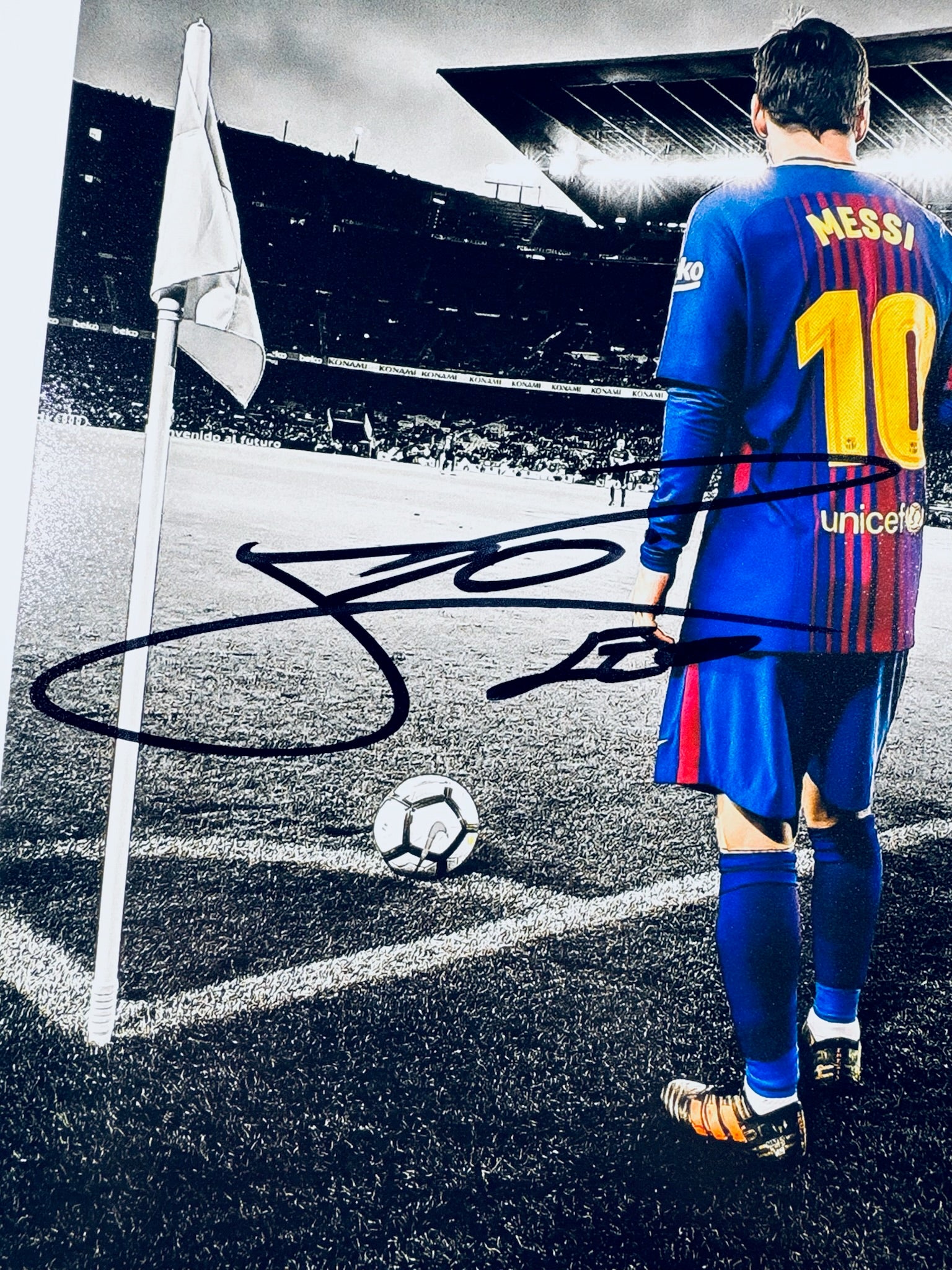 A close-up view showing the authentic hand-signed signature of Lionel Messi on a matte photograph