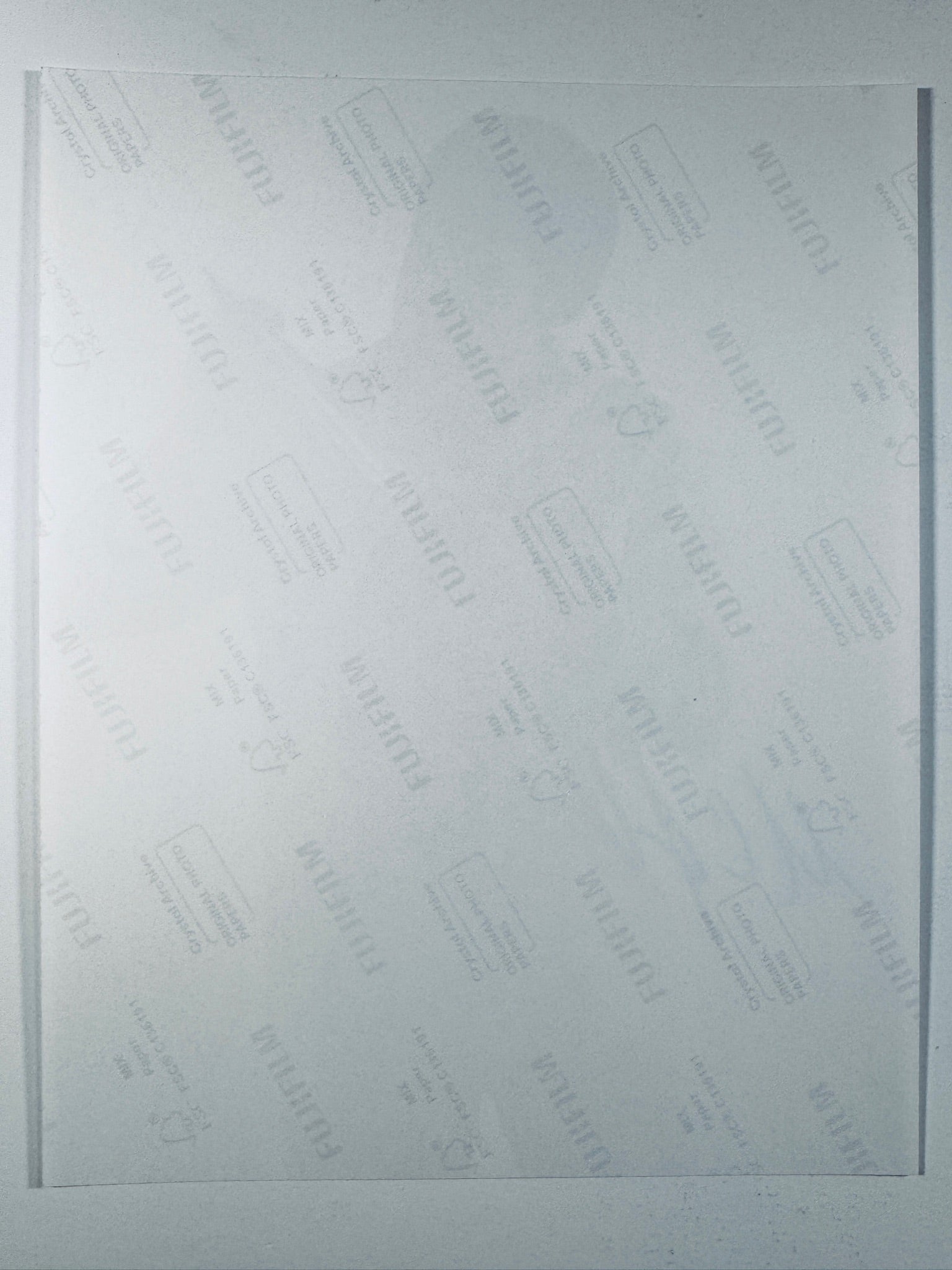 The plain white reverse side of a photographic print showing translucent Fujifilm crystal archive paper watermarks and logos.