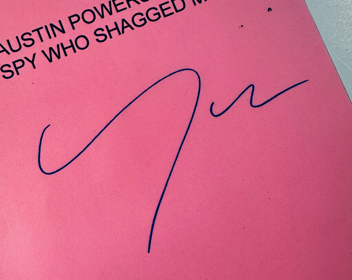 Close-up macro shot of Michael York signature written in blue ballpoint ink on pink cardstock.