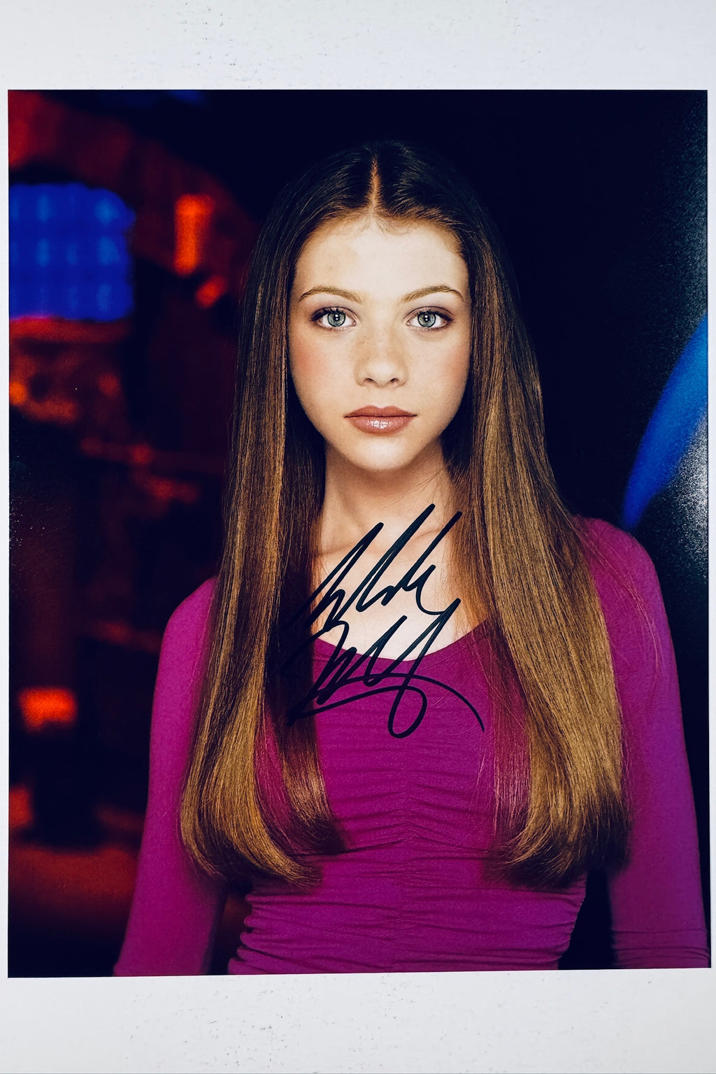 Signed 8x10 matte promotional photo of actress Michelle Trachtenberg as Dawn Summers from Buffy the Vampire Slayer wearing a purple top, featuring a bold black ink autograph.