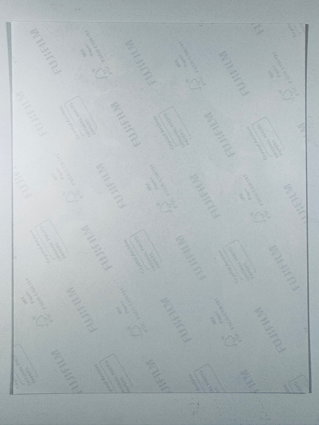 The plain white reverse side of a photographic print showing translucent Fujifilm crystal archive paper watermarks and logos.