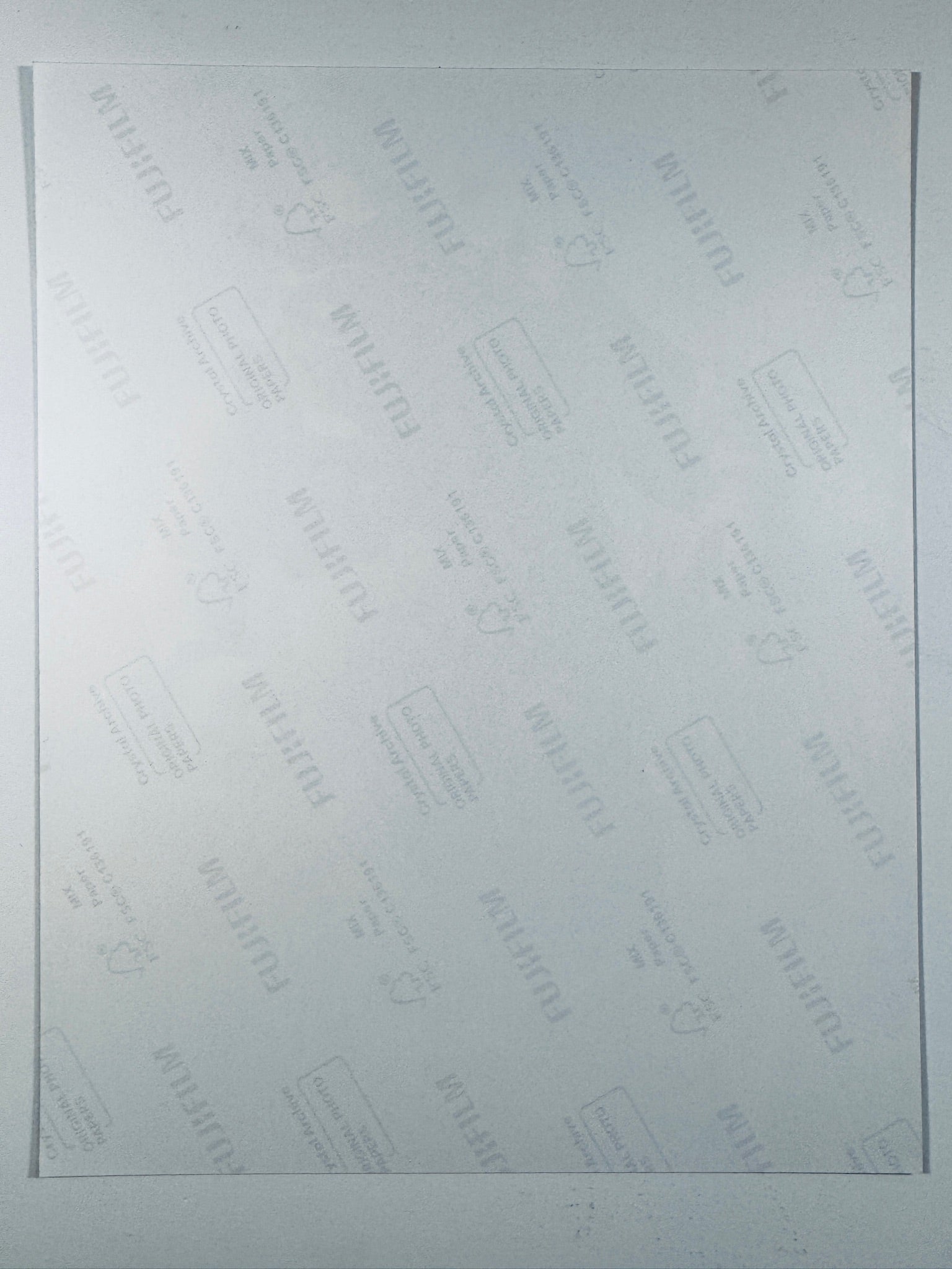 The plain white reverse side of a photographic print showing translucent Fujifilm crystal archive paper watermarks and logos.