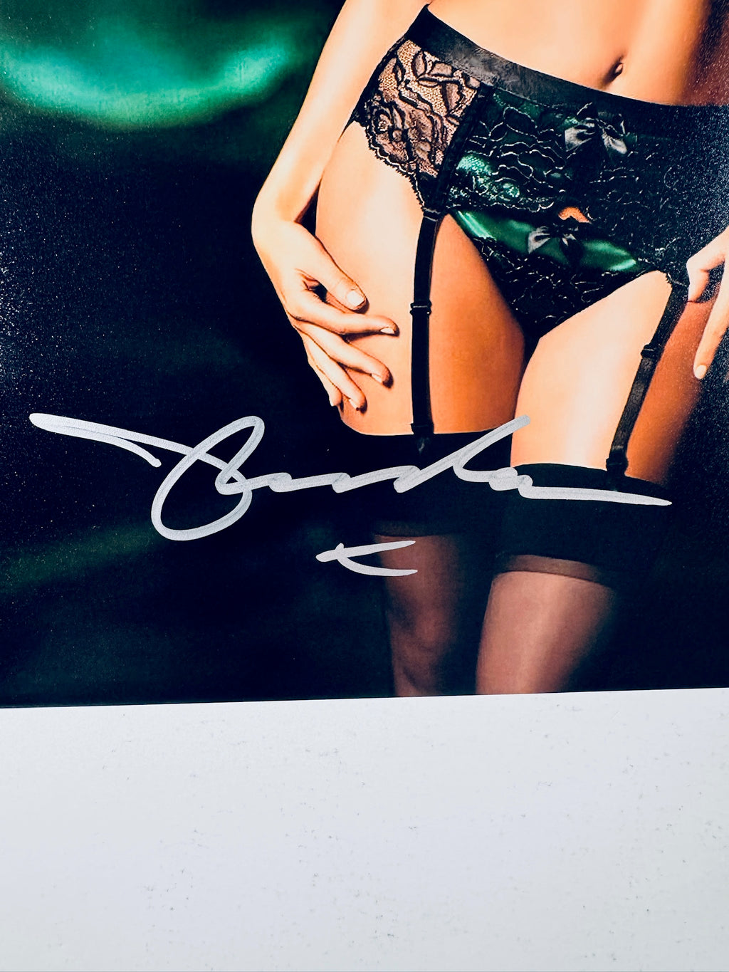 Close-up view of Miranda Kerr's silver signature across her lower body and stockings on the promotional photograph.