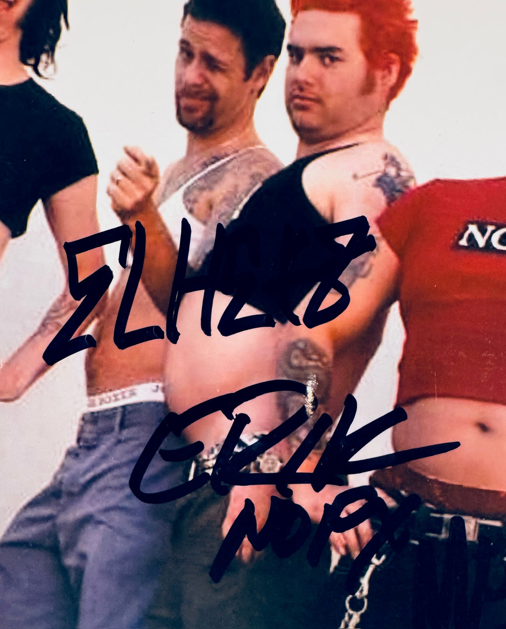 Close-up detail view showing signatures of NOFX guitarist El Hefe and guitarist Eric Melvin in black Sharpie across their photo.