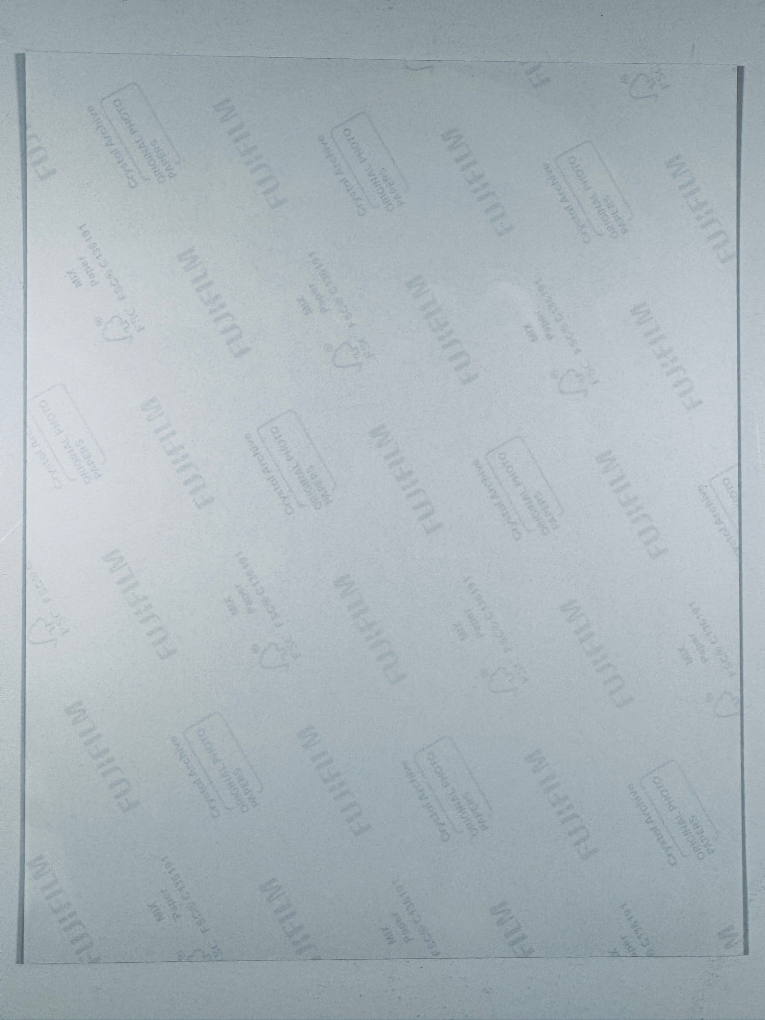The plain white reverse side of a photographic print showing translucent Fujifilm crystal archive paper watermarks and logos.