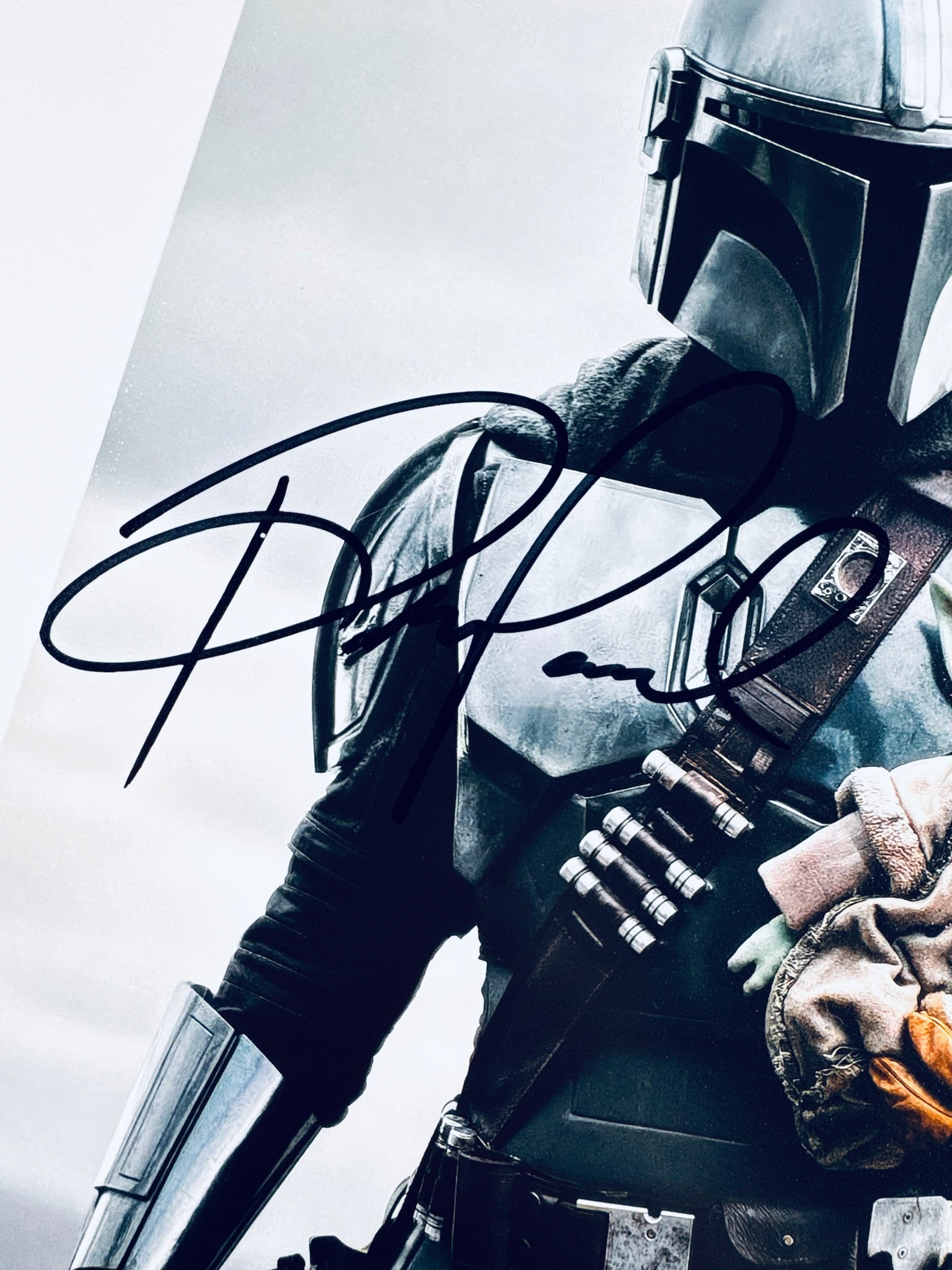 A close-up view showing the authentic hand-signed signature of Pedro Pascal on a matte photograph.