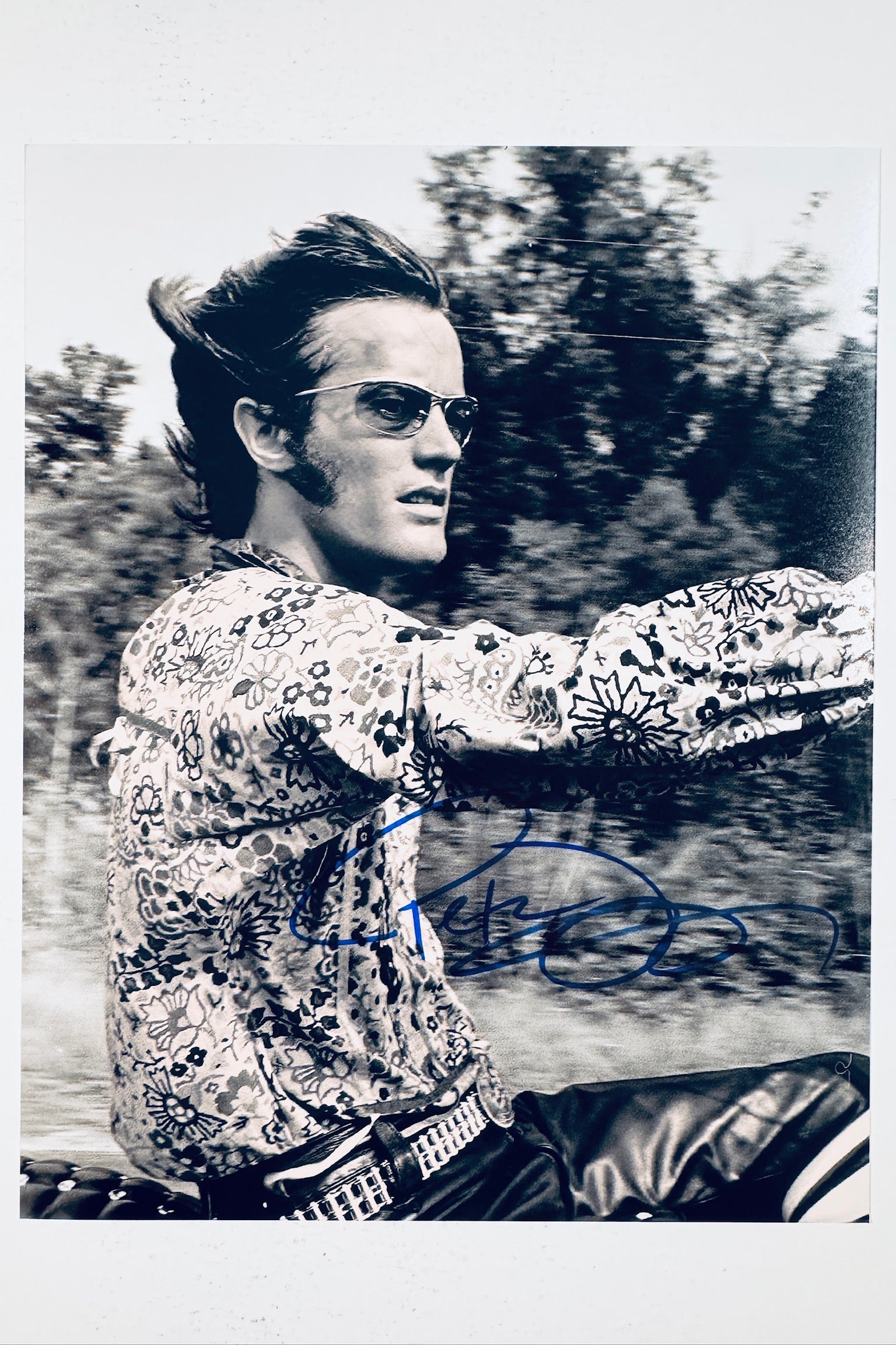 Signed 8x10 matte photo of Peter Fonda riding a motorcycle in a patterned shirt and sunglasses, featuring a bold blue ink autograph across the lower portion.