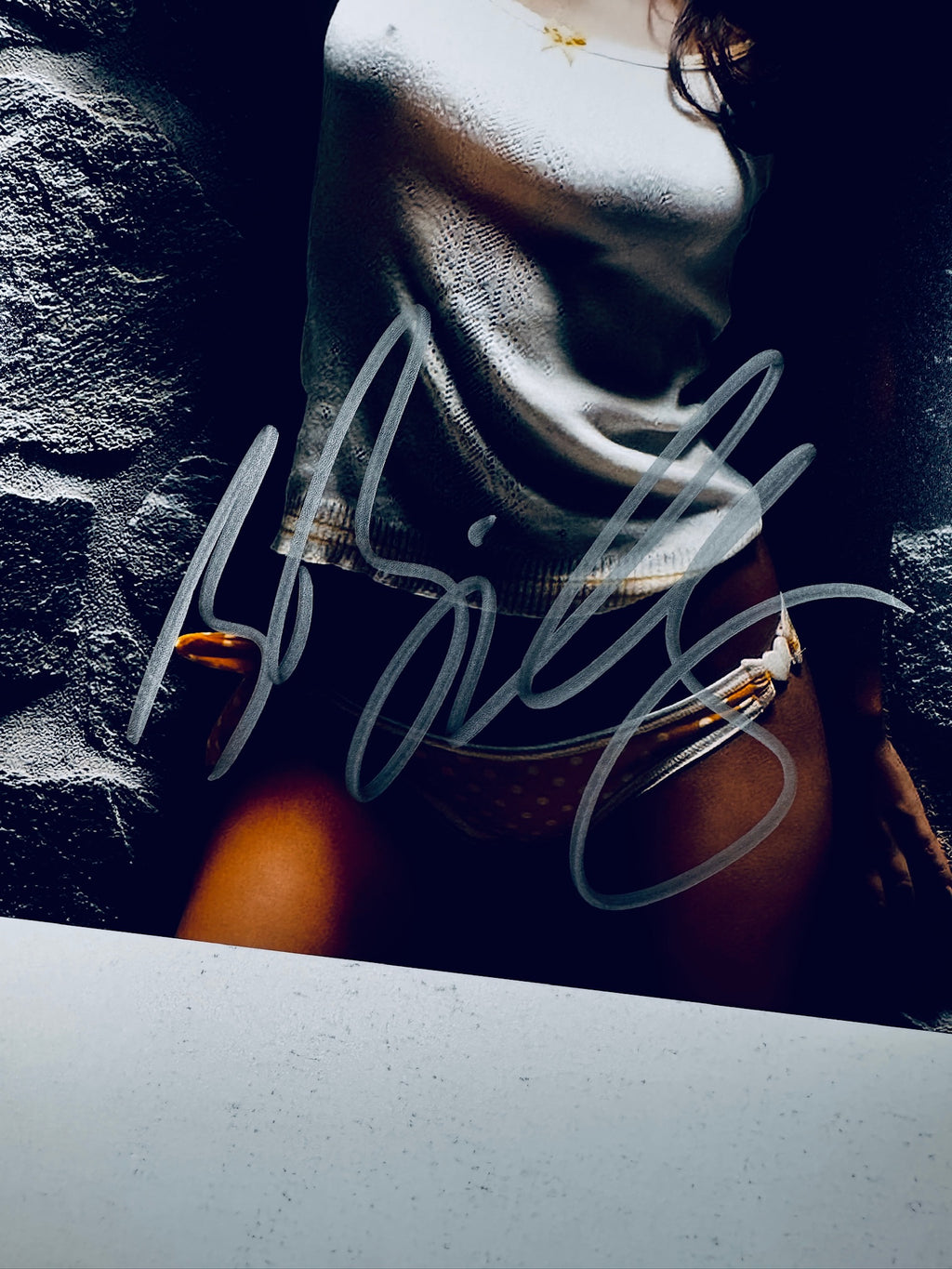 Close-up view of Rachel Bilson's silver autograph across her midsection and lower torso on the promotional photograph.