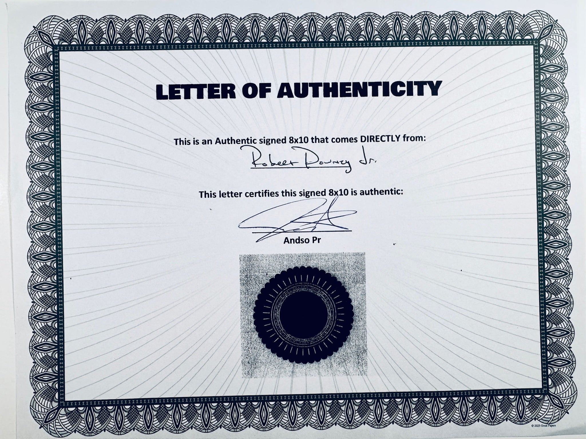 A Letter of Authenticity with a decorative blue-patterned border, certifying an authentic signed 8x10 coming directly from Robert Downey Jr., featuring a dark circular seal graphic at the bottom.