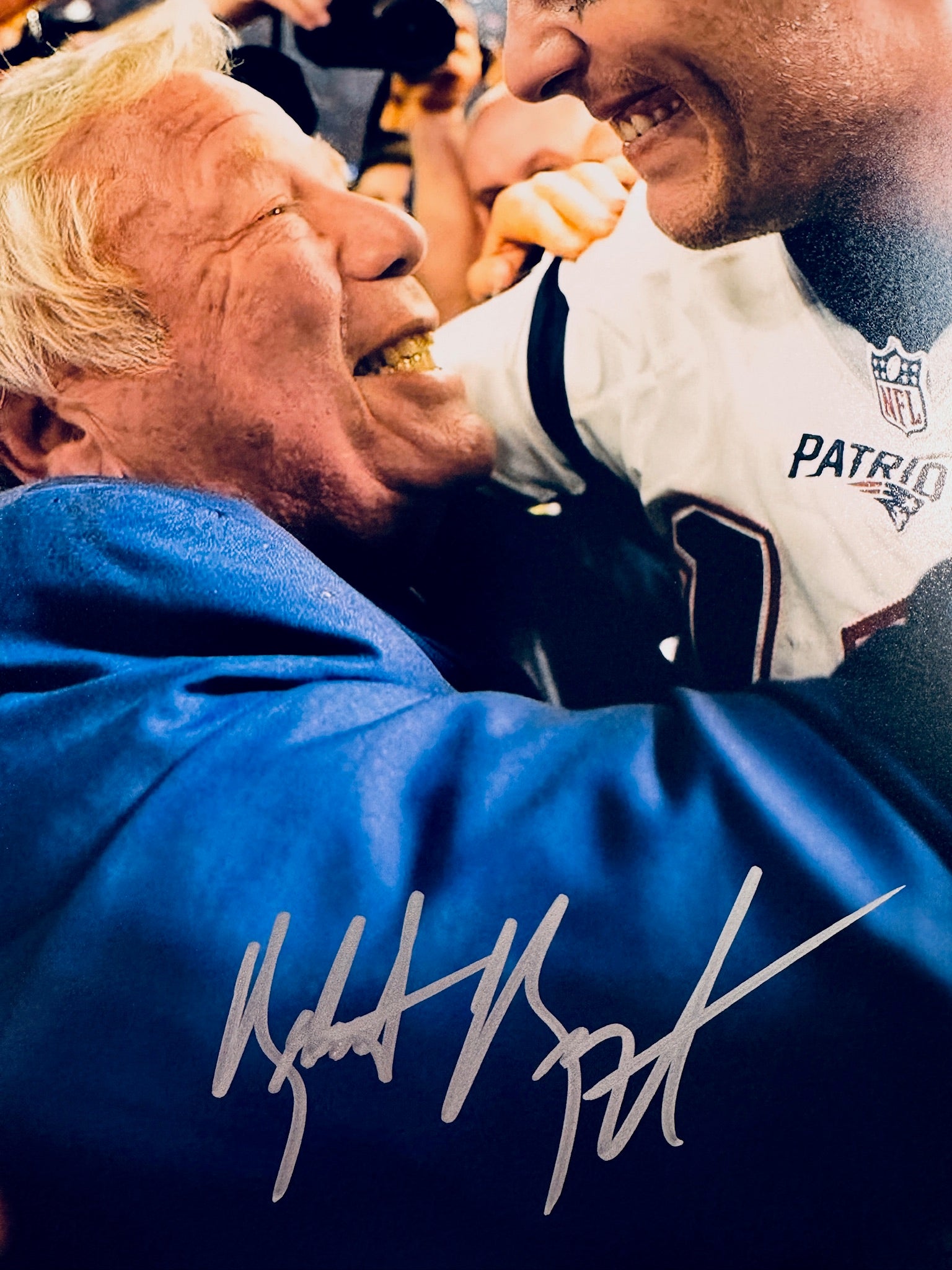 Close-up view of Robert Kraft's signature in silver marker across the Patriots promotional matte photo.