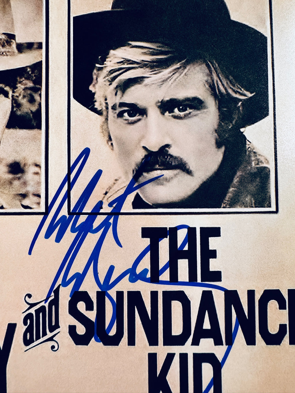 Close-up view of Robert Redford's individual signature in blue marker on the Butch Cassidy and the Sundance Kid wanted poster matte photo.