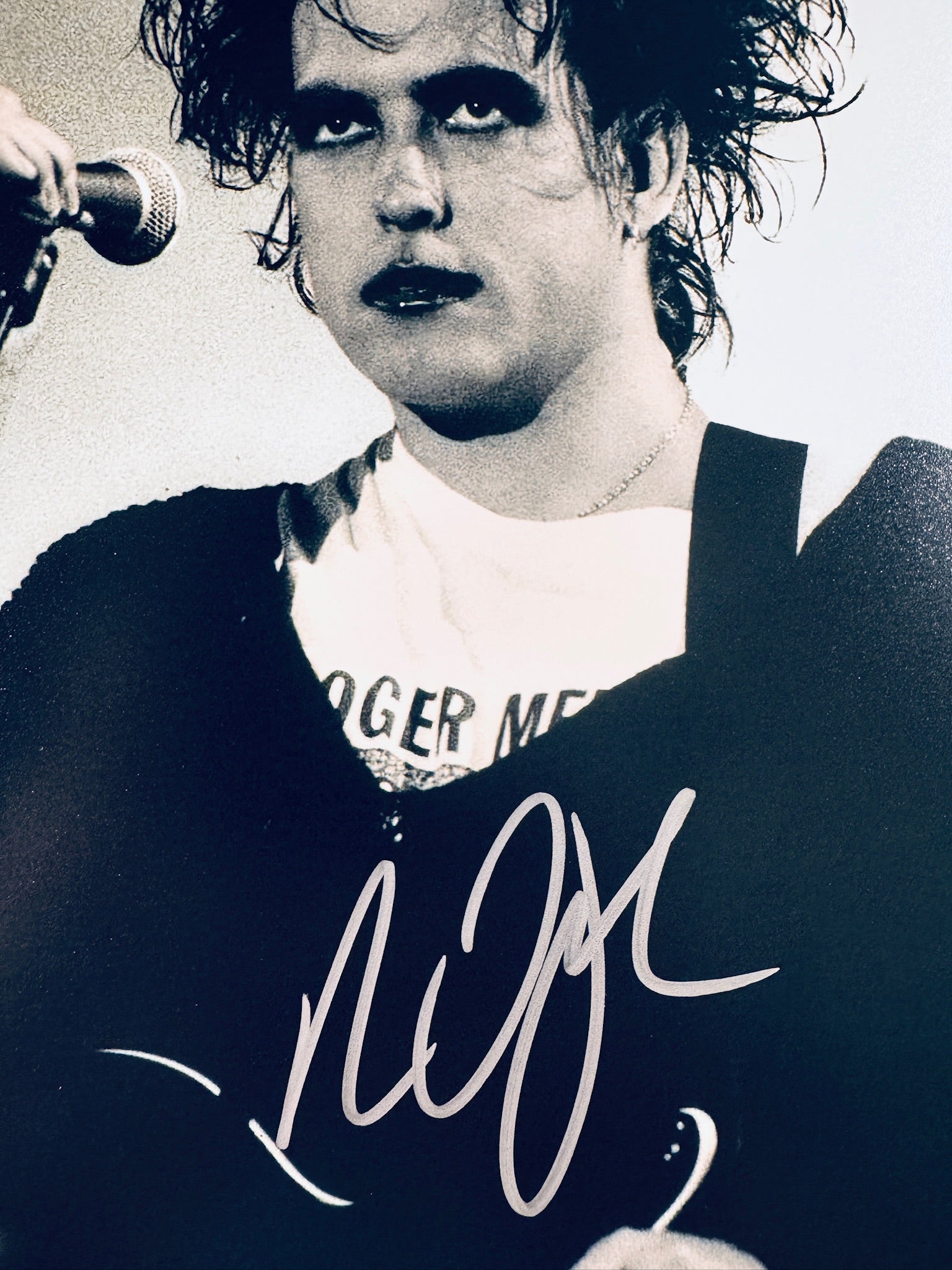 Close-up view of Robert Smith of The Cure's signature in silver marker on his live performance promotional matte photo.