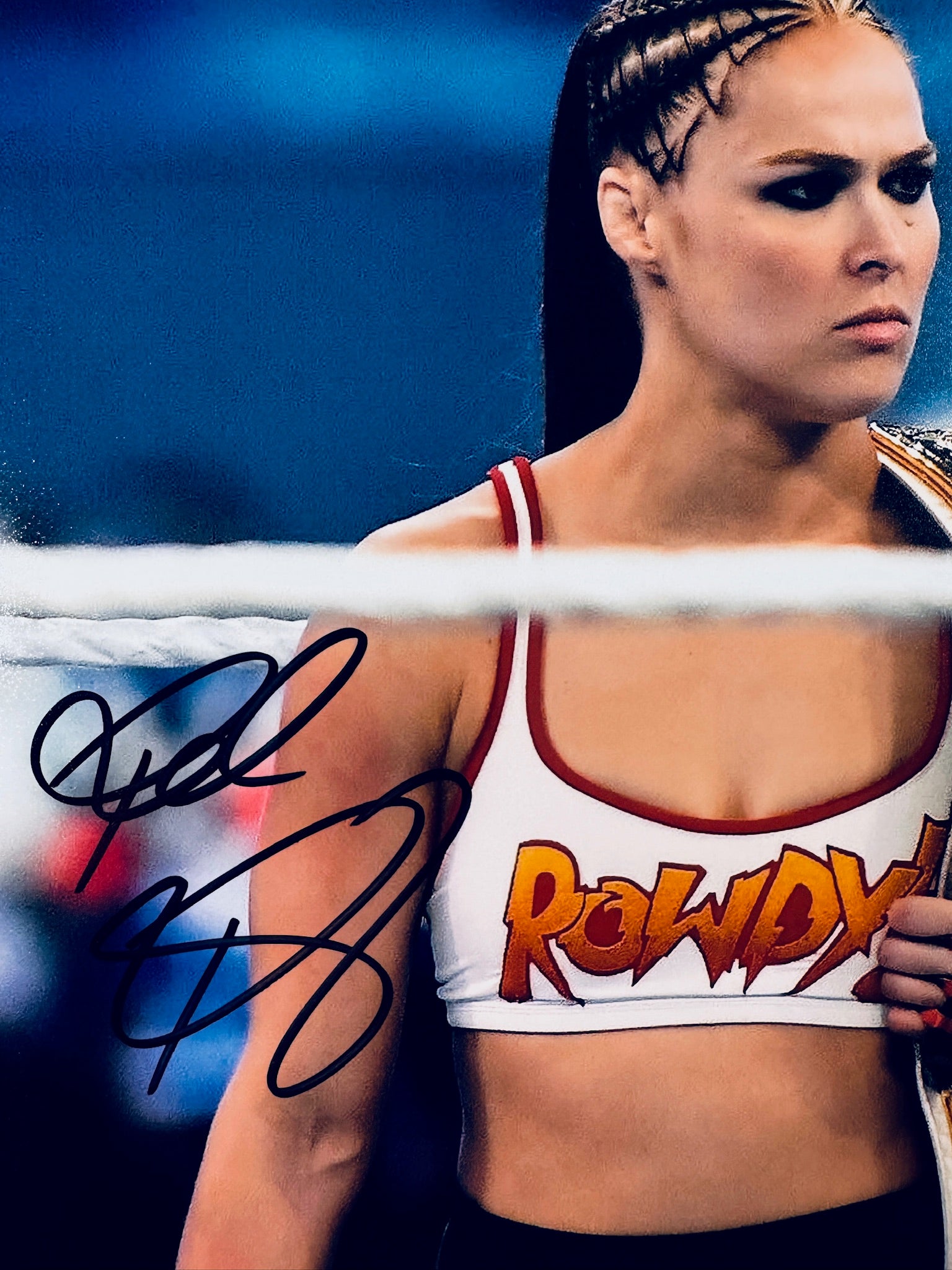 Close-up view of Ronda Rousey's signature in black marker on her WWE wrestling promotional photo.