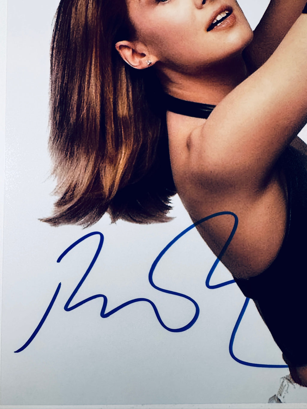 Close-up view of Rosamund Pike's signature in blue marker on her promotional matte photo.