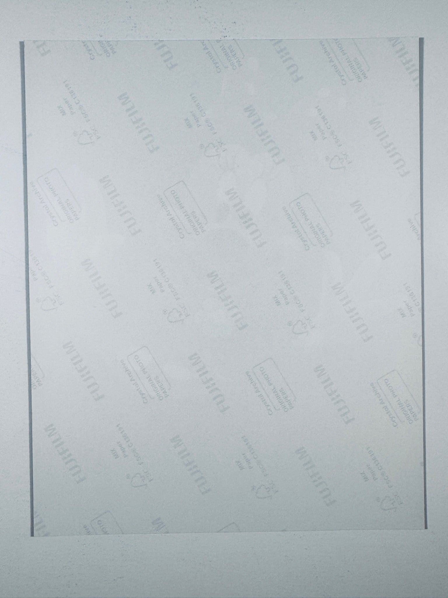 The plain white reverse side of a photographic print showing translucent Fujifilm crystal archive paper watermarks and logos.