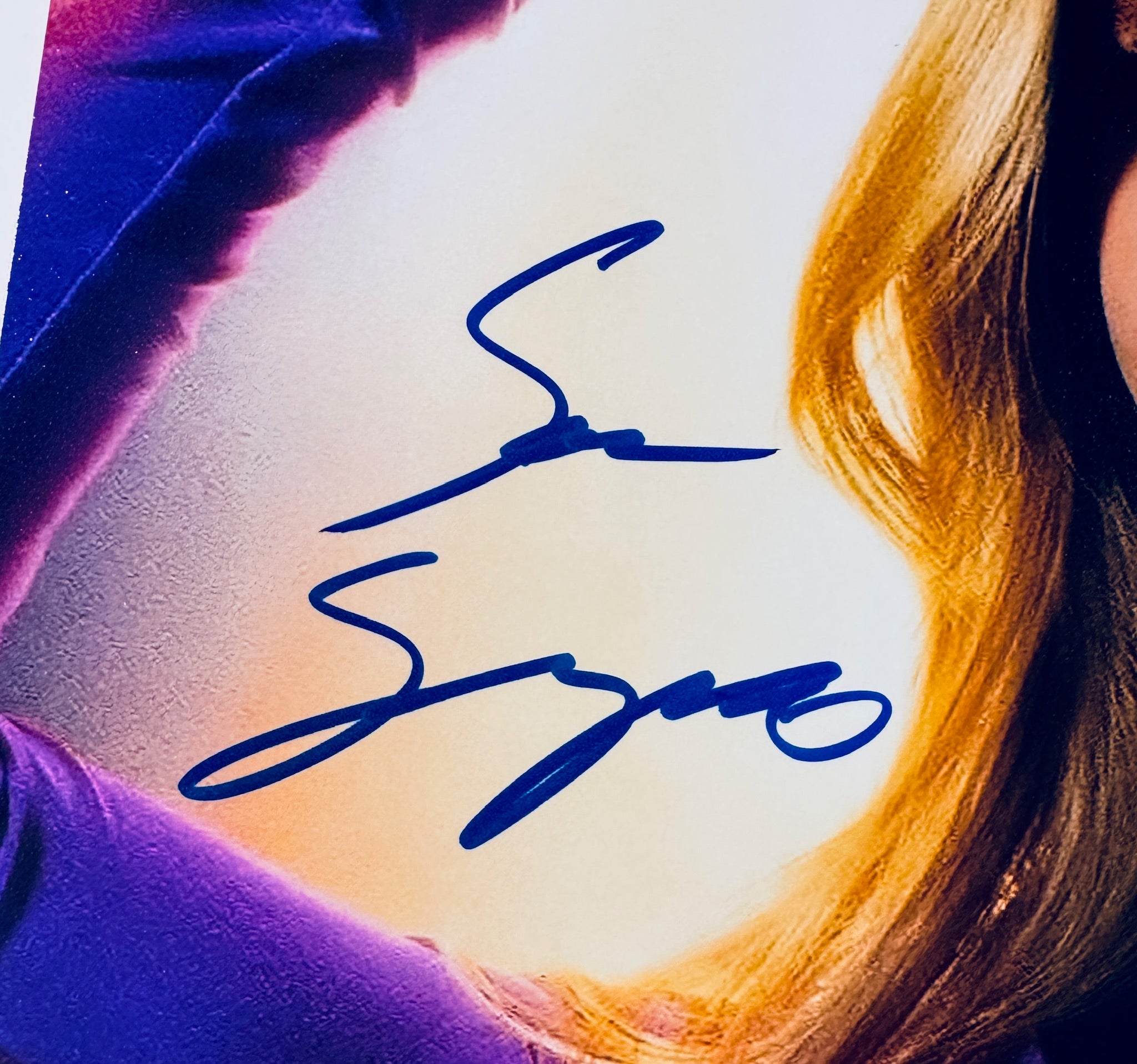 Close-up of Sara Sampaio's signature in blue marker on the signed Superman 8x10 photo.