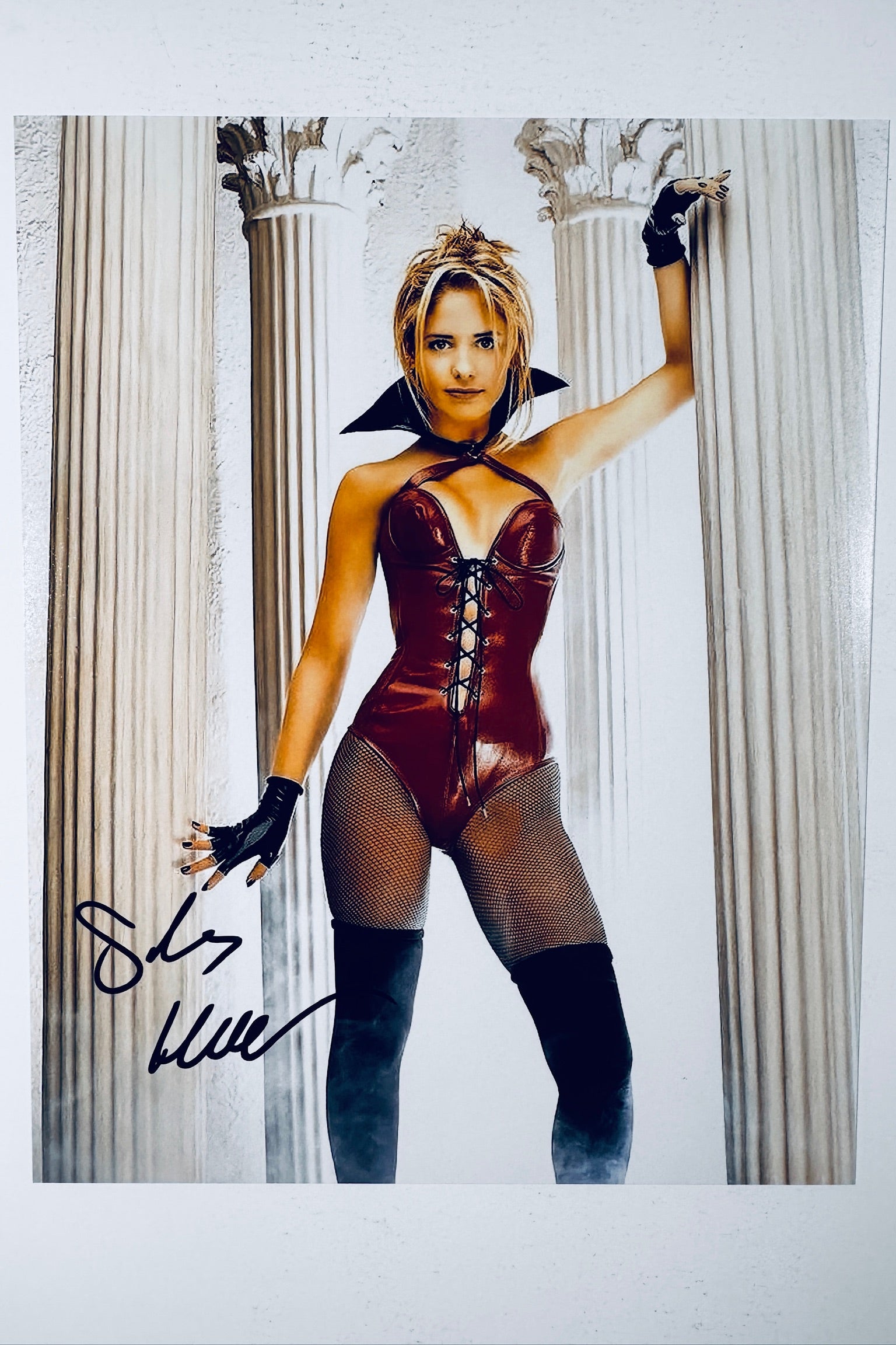 Signed full photo of Sarah Michelle Gellar as Buffy the Vampire Slayer posing between white columns, featuring a black autograph.
