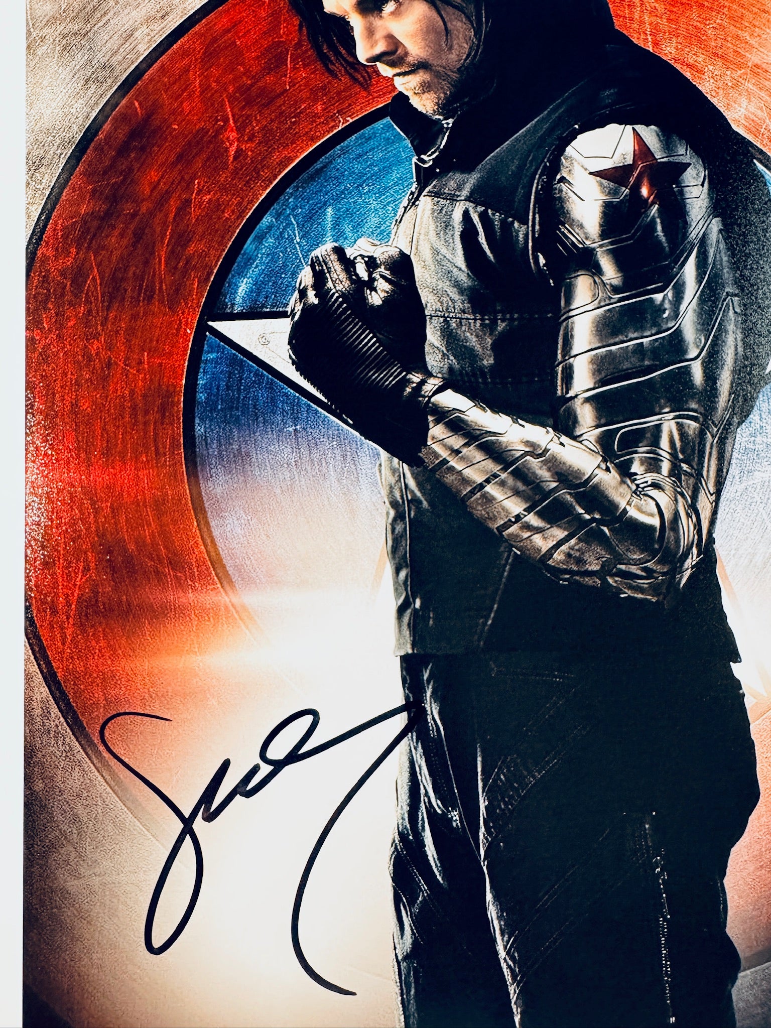 Close-up view of Sebastian Stan's signature in black marker on his Winter Soldier promotional matte photo.