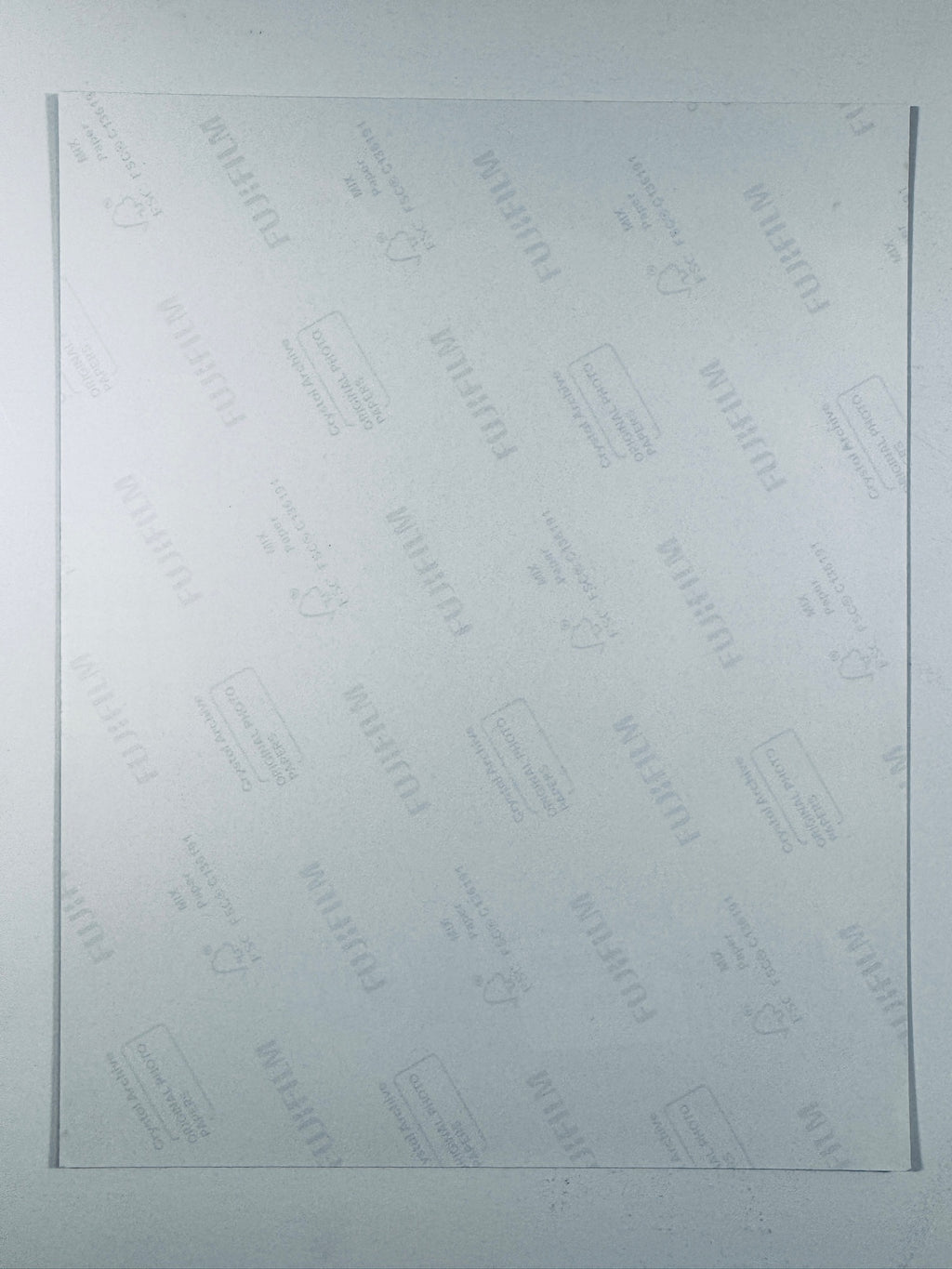 The plain white reverse side of a photographic print showing translucent Fujifilm crystal archive paper watermarks and logos.