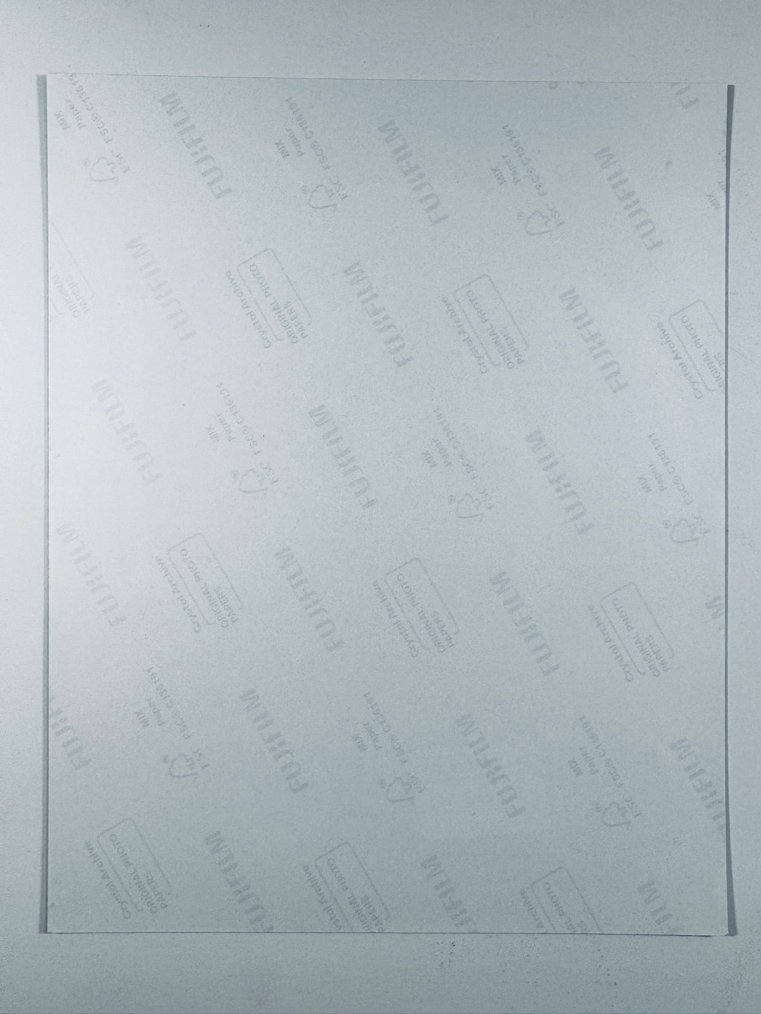 The plain white reverse side of a photographic print showing translucent Fujifilm crystal archive paper watermarks and logos.