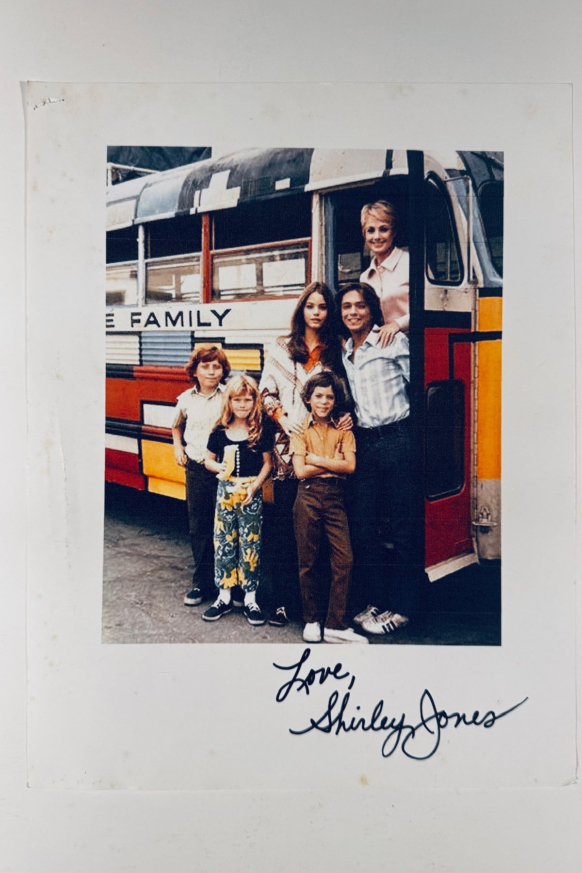 Full front view of autographed 8x10 color photo featuring The Partridge Family cast standing outside their famous bus, signed Love, Shirley Jones in black marker below.