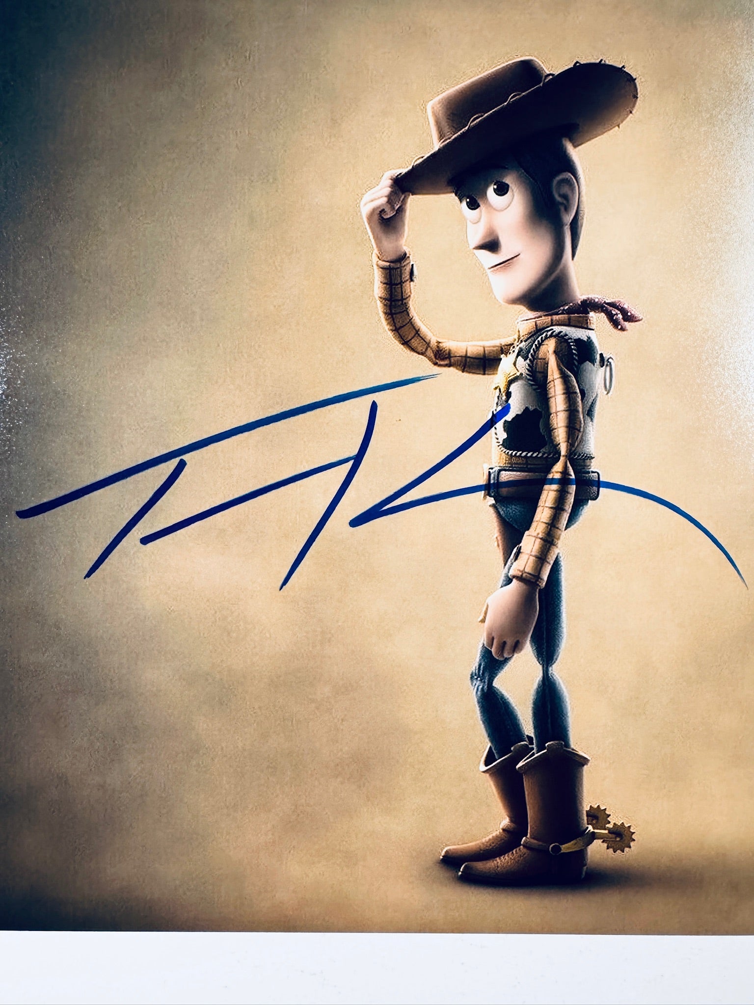 Close-up view of Tom Hanks's blue signature across the center of the Toy Story promotional photograph.