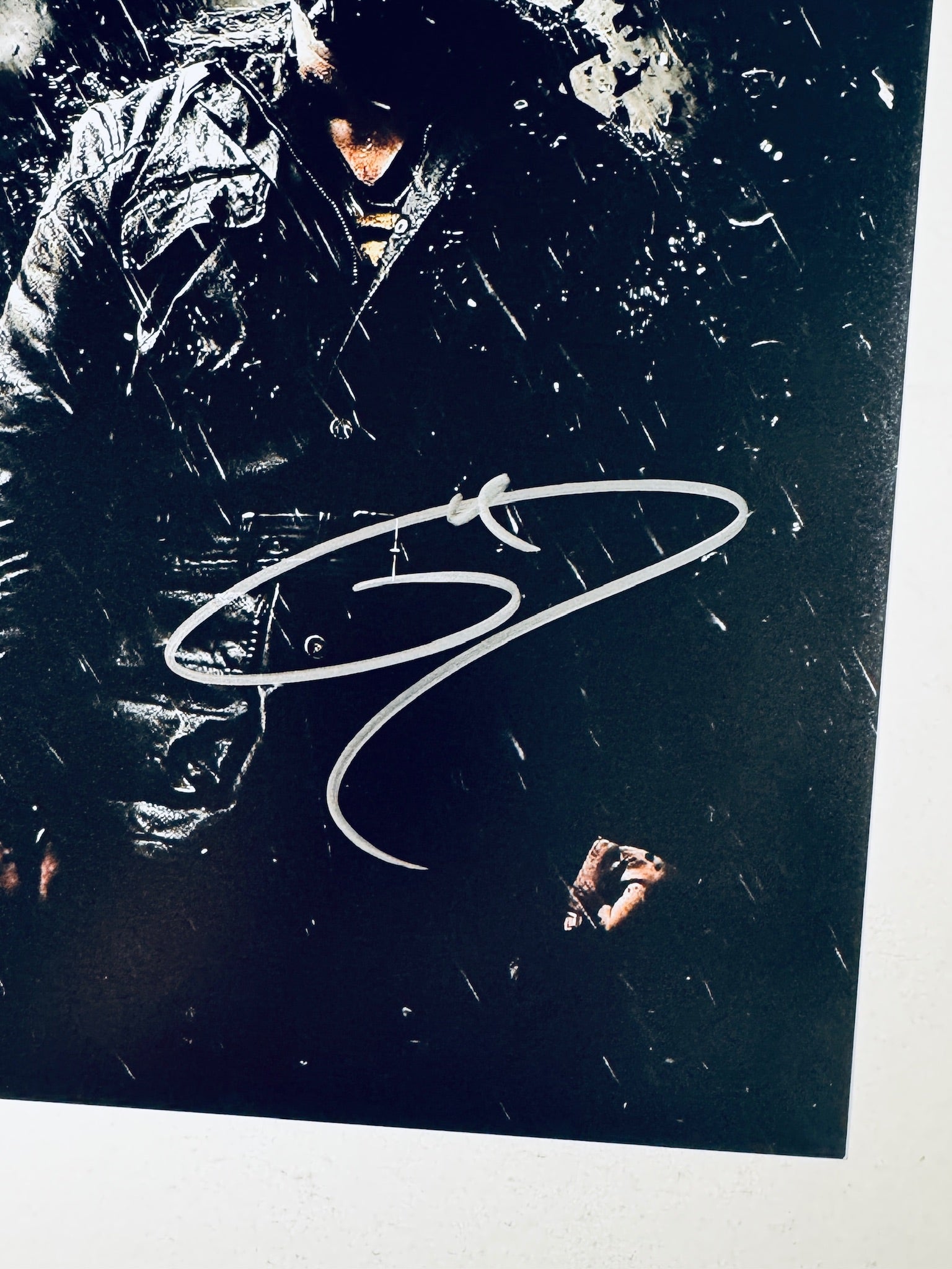 Close-up view of Tom Hardy's silver signature across the lower portion of The Dark Knight Rises promotional photograph.