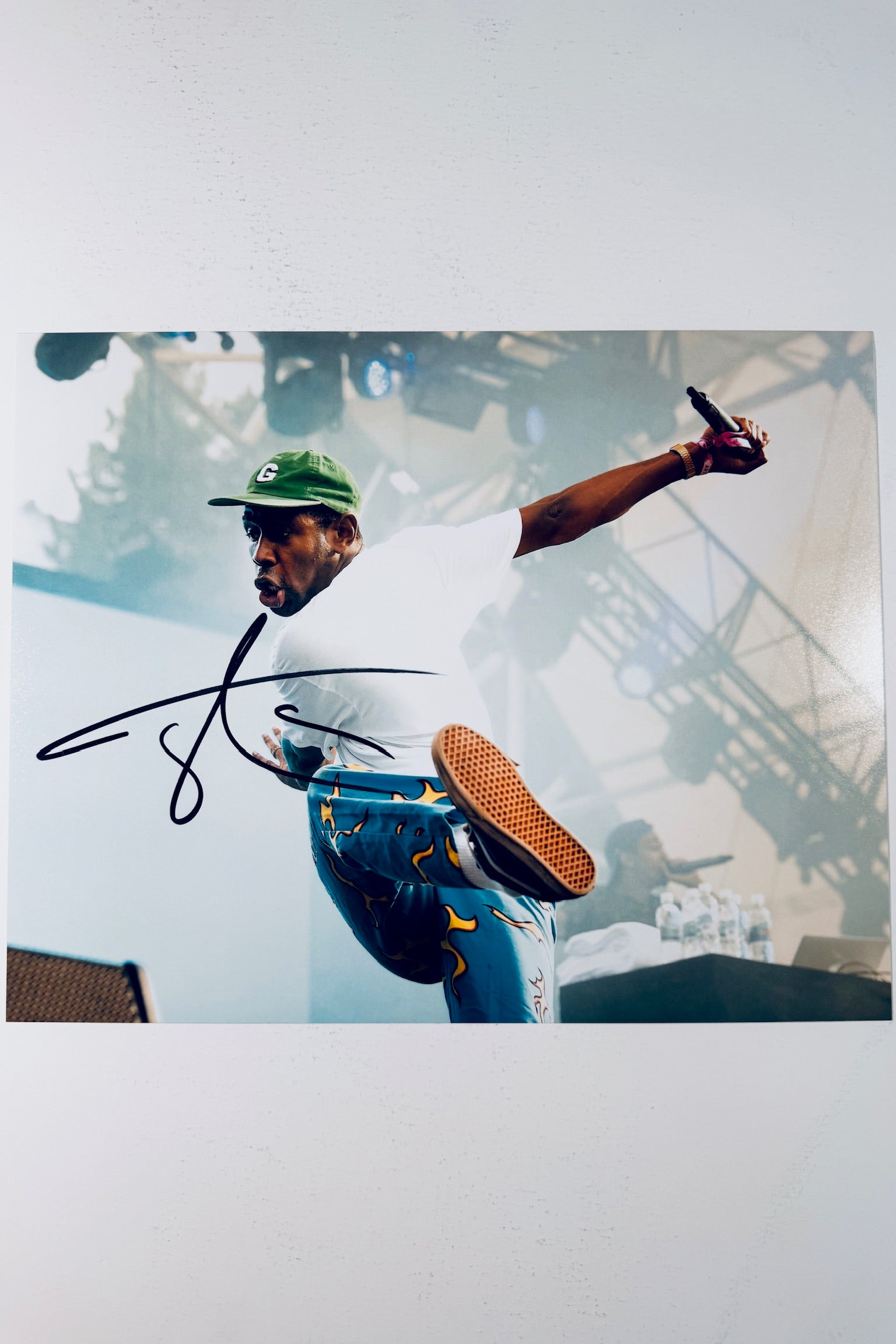 Tyler, The Creator hand-signed 8x10 matte photo performing live on stage wearing flame pants and a green hat.