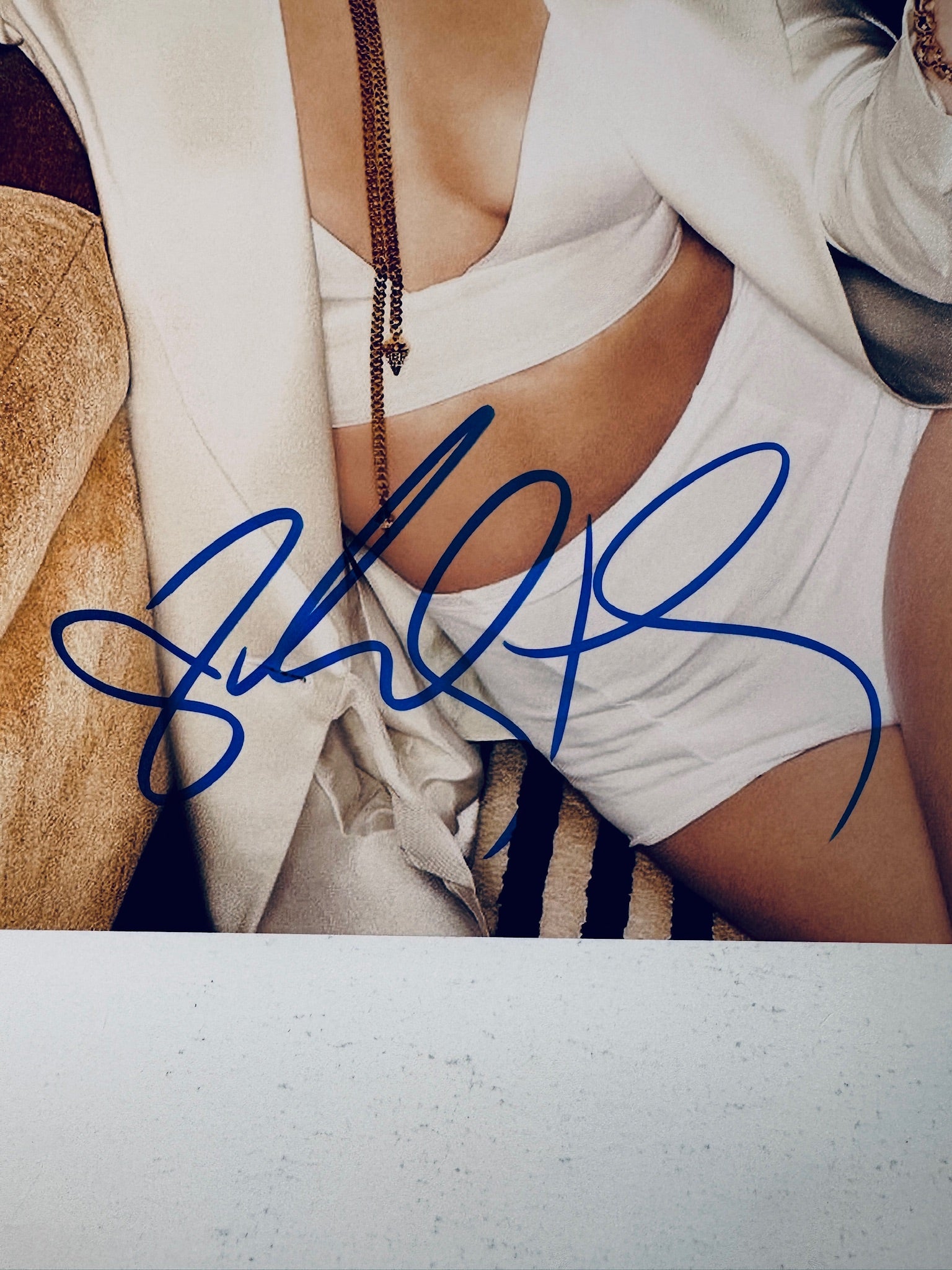 Close-up view of Vanessa Hudgens's blue signature across her midsection and white outfit on the promotional photograph.