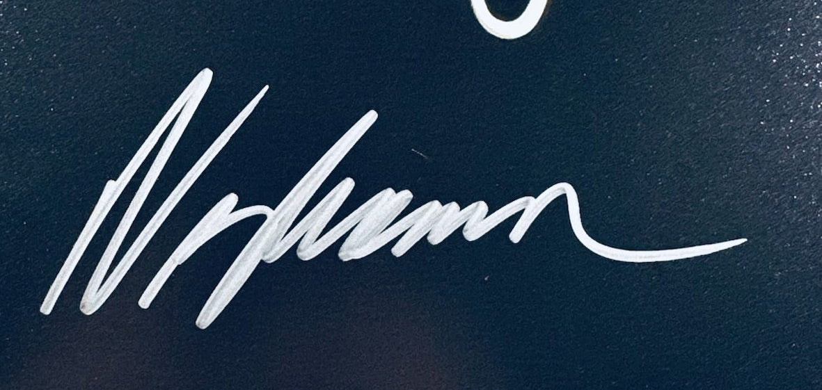 A close-up view showing the authentic hand-signed signature of Wes Craven on a matte photograph.
